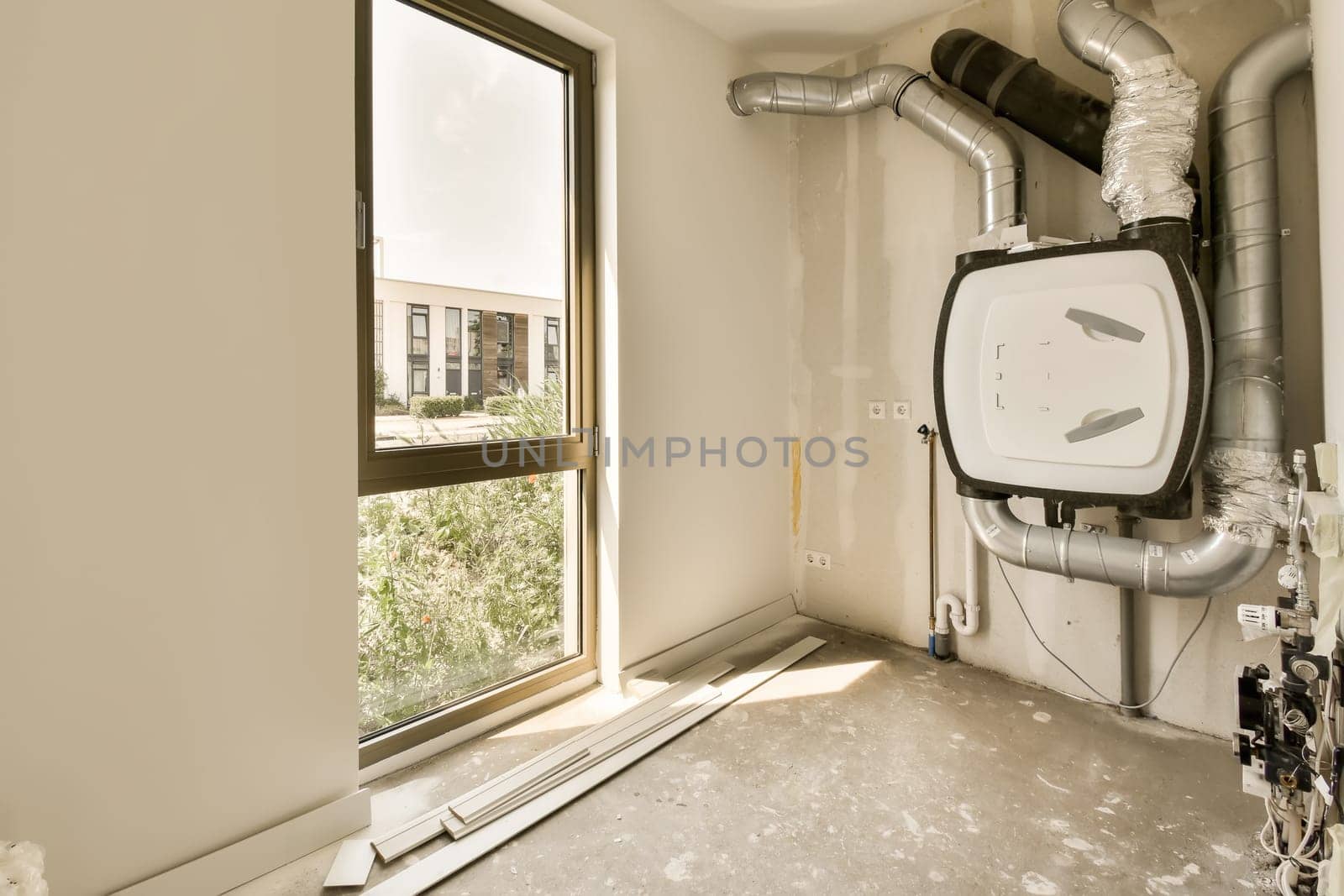 an empty room with pipes and a window by casamedia