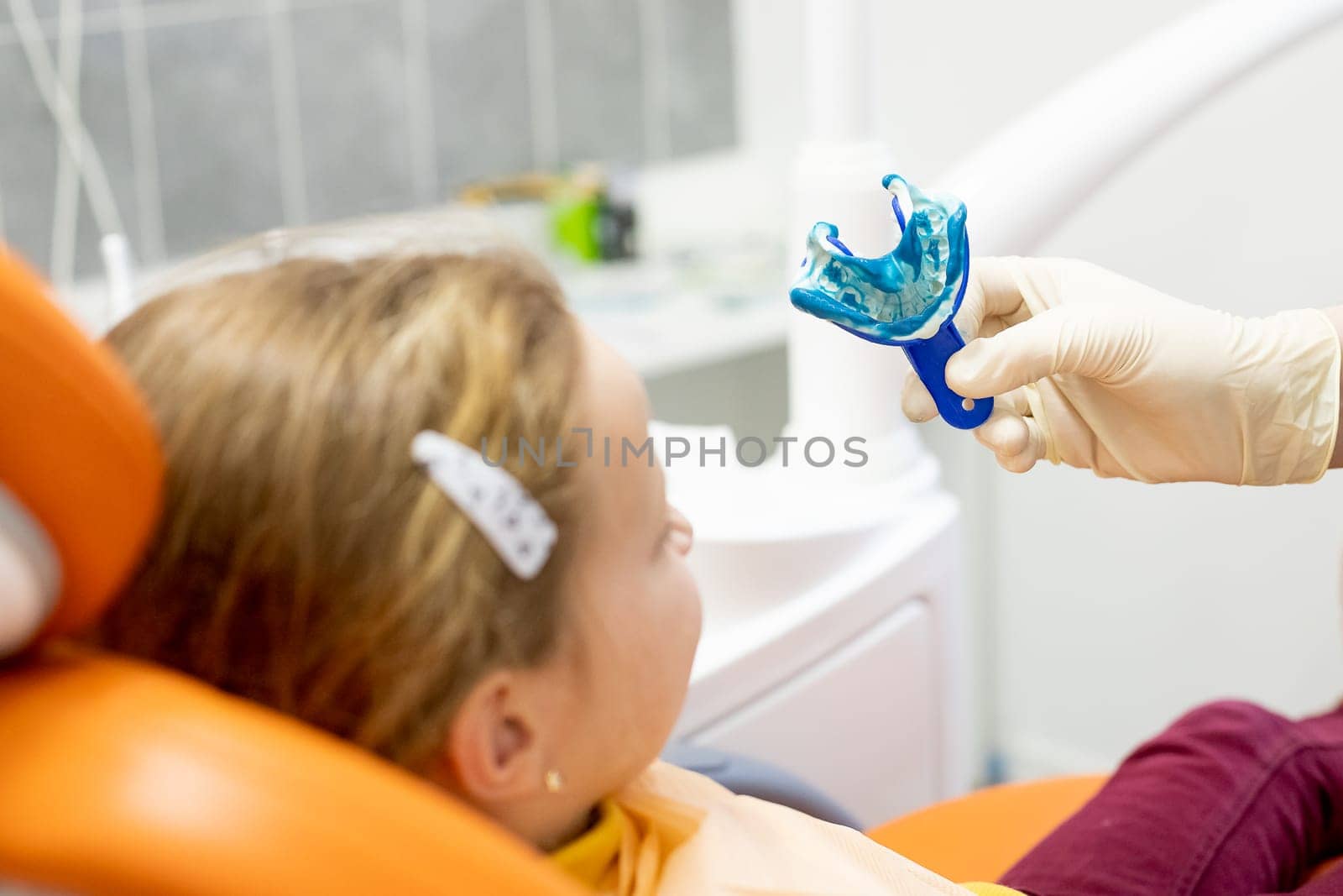 The orthodontist prepares a special paste for making an impression of the patient's teeth.Child during orthodontist visit and oral cavity check-up by YuliaYaspe1979