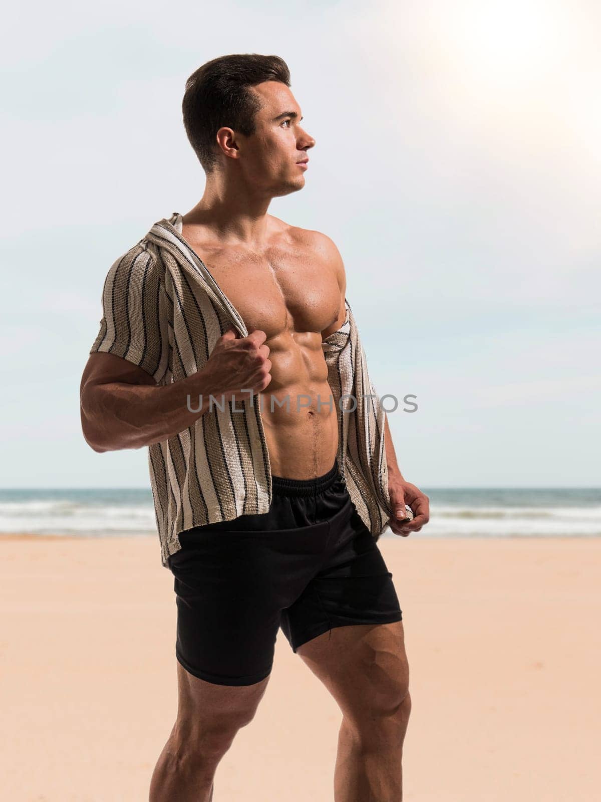 Muscles Glistening in the Sun: A Shirtless Bodybuilder on a Beautiful Beach by artofphoto