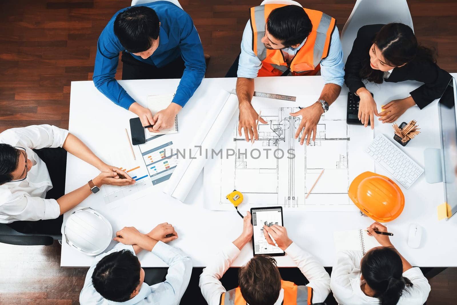 Top view banner of diverse group of civil engineer and client working together on architectural project, reviewing construction plan and building blueprint at meeting table. Prudent