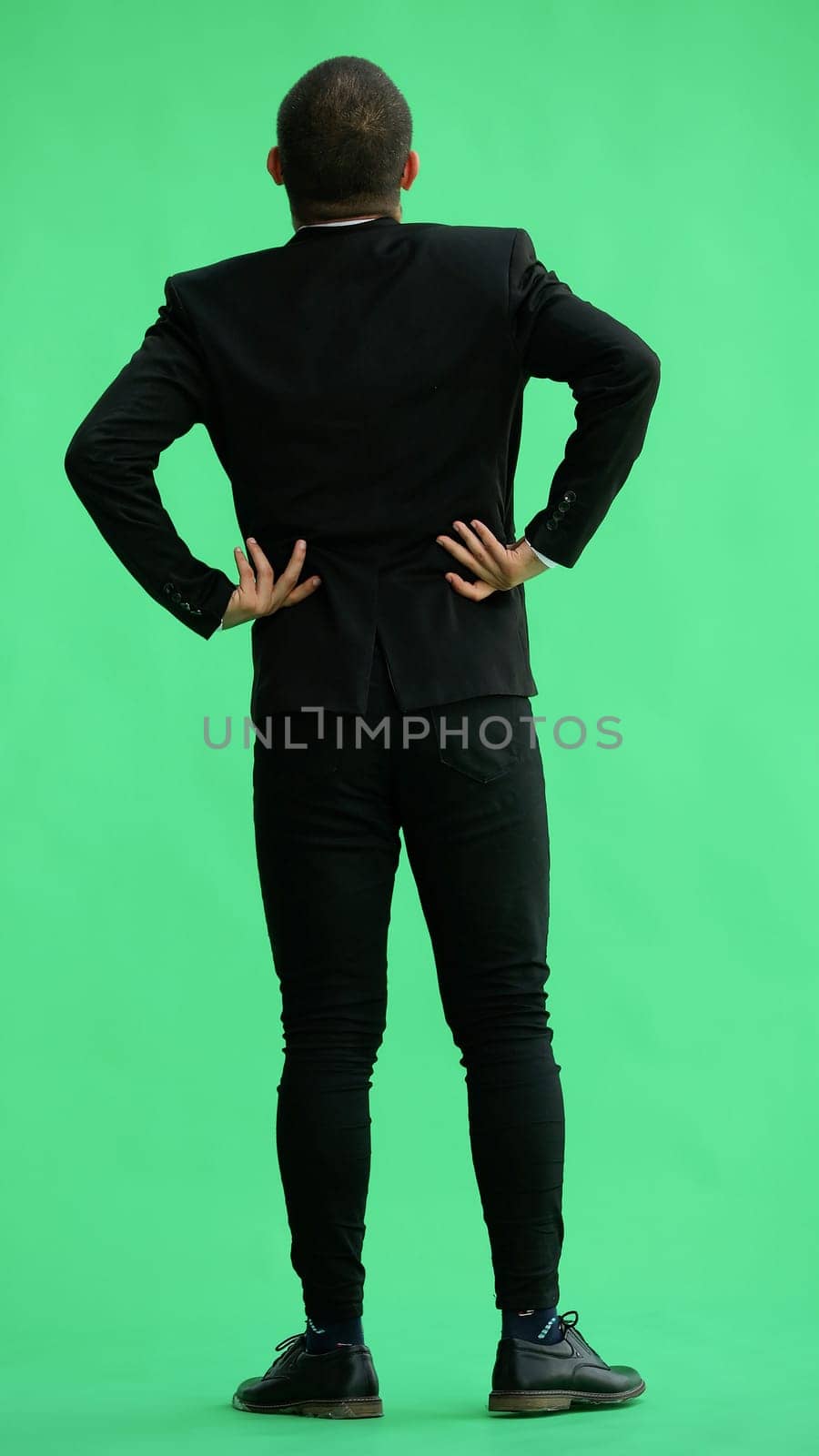 young man in full growth. isolated on green background. view from the back.