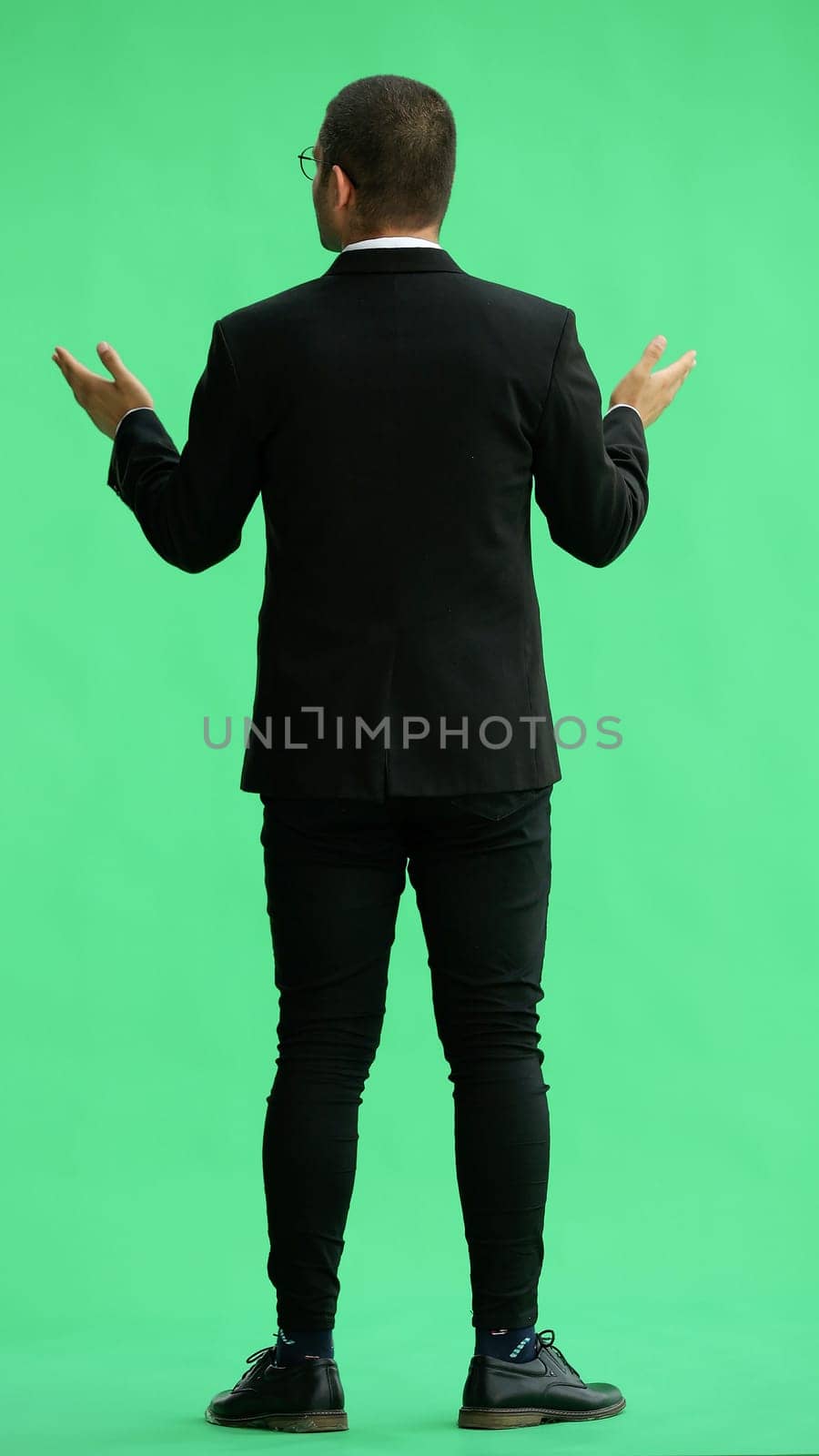 young man in full growth. isolated on green background demonstrates with hands by Prosto