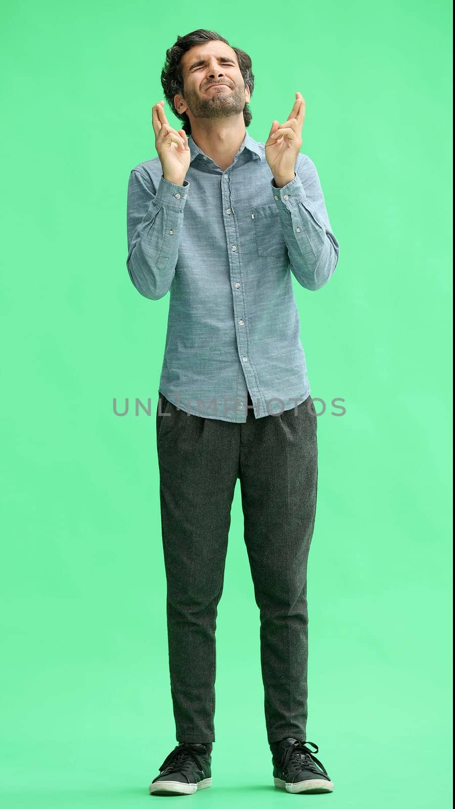 young man in full growth. isolated on a green background cupped hands together by Prosto