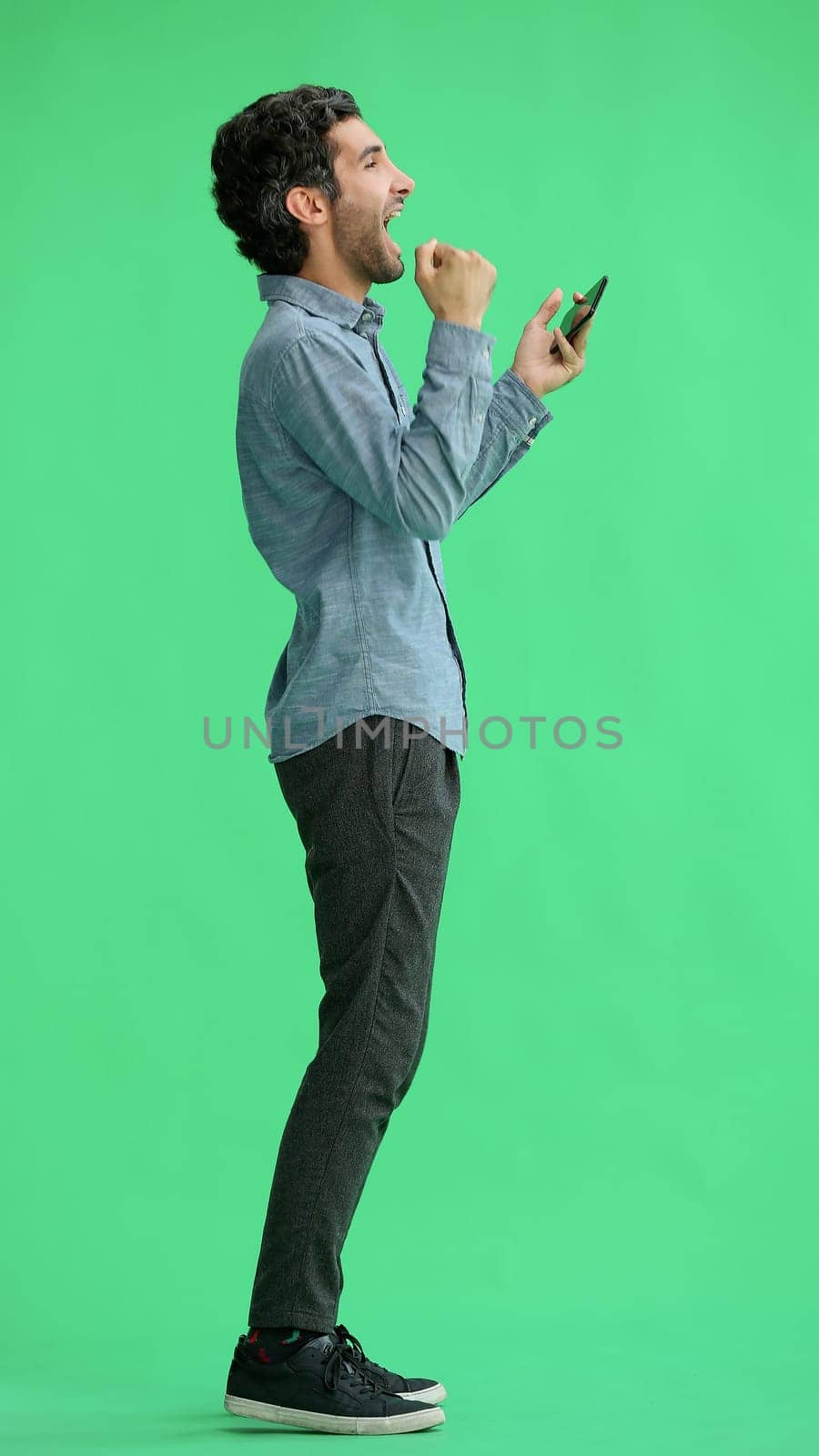 young man in full growth. isolated on green background taking selfie by Prosto