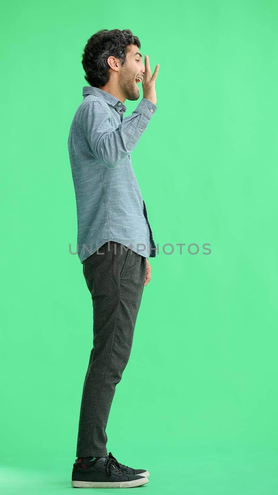 man isolated on a green background shows with his hands a sign of what to expect by Prosto