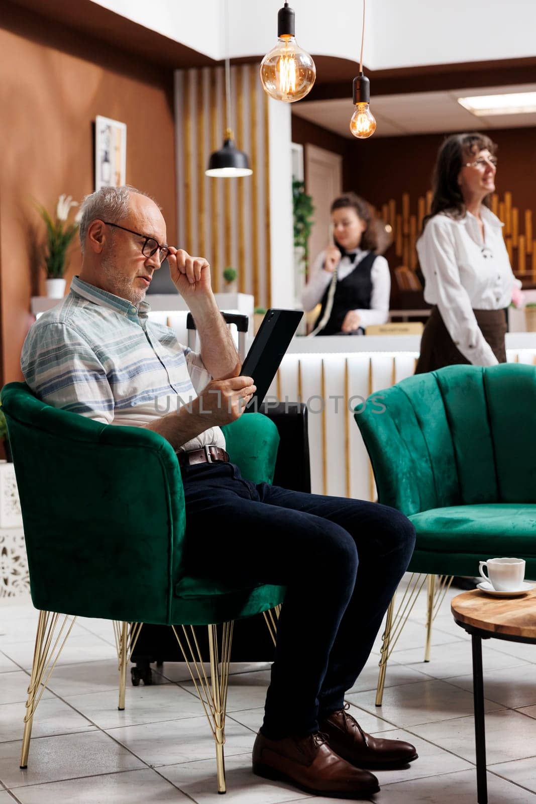 Elderly man using tablet in hotel lobby by DCStudio