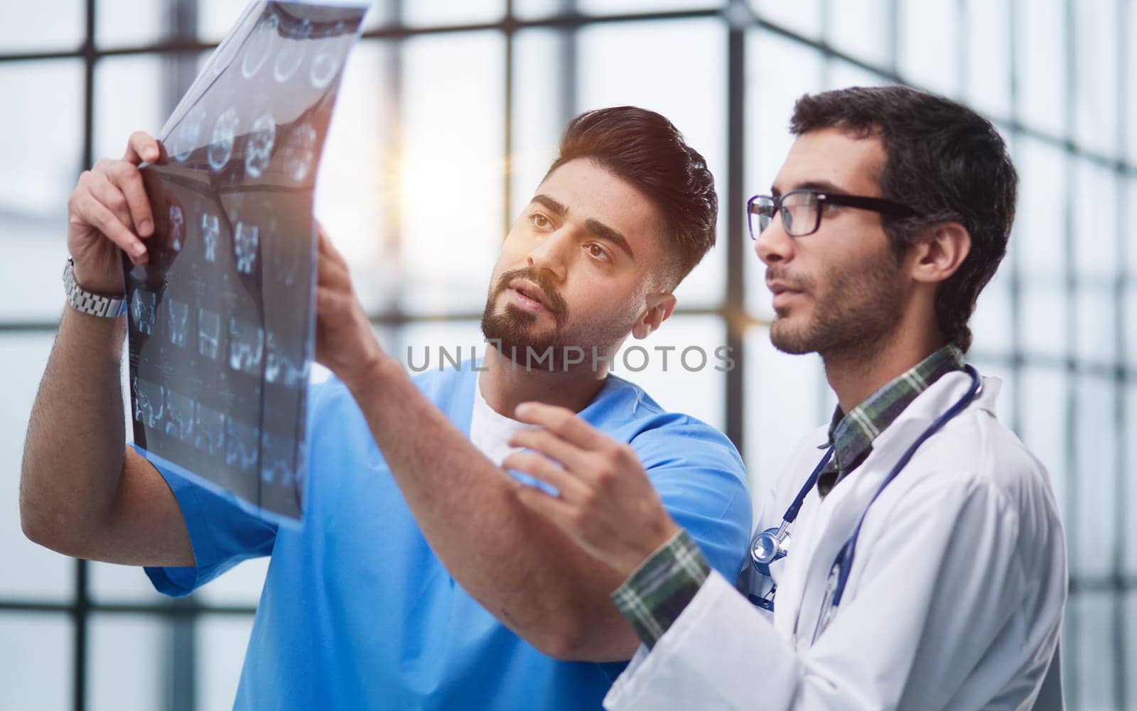 Male medics consult with each other while looking at x ray image.
