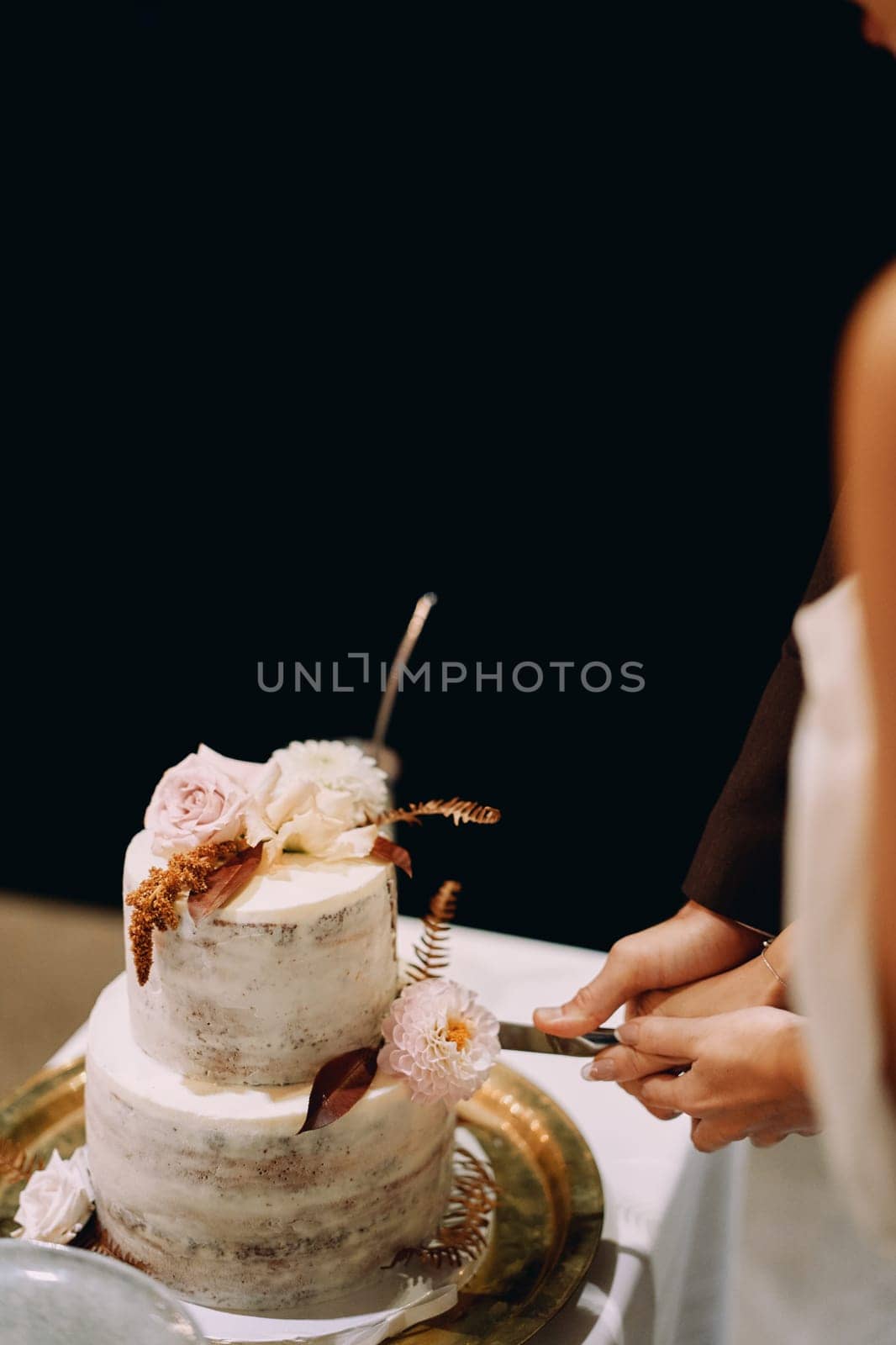 Bride and groom cut the wedding cake together. Cropped. Faceless. High quality photo