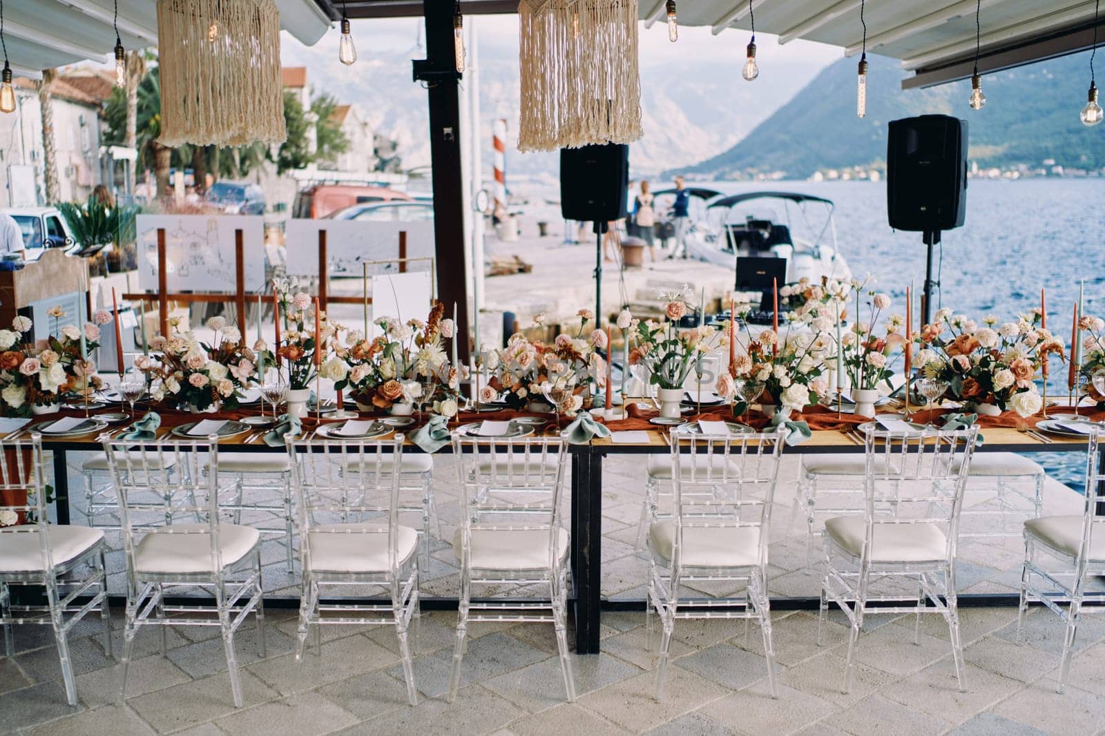 Long festive table with bouquets of flowers stands on a pier by the sea. High quality photo