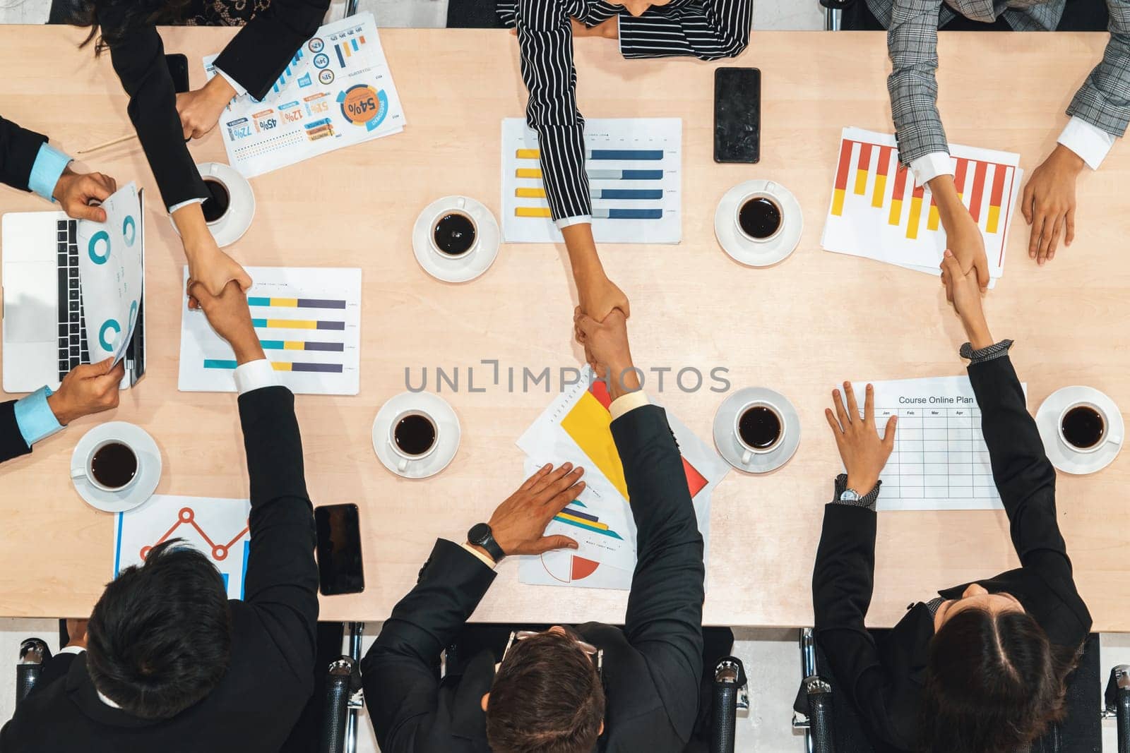 Group business people handshake at meeting table in office together with confident shot from top view . Young businessman and businesswoman workers express agreement of investment deal. Jivy