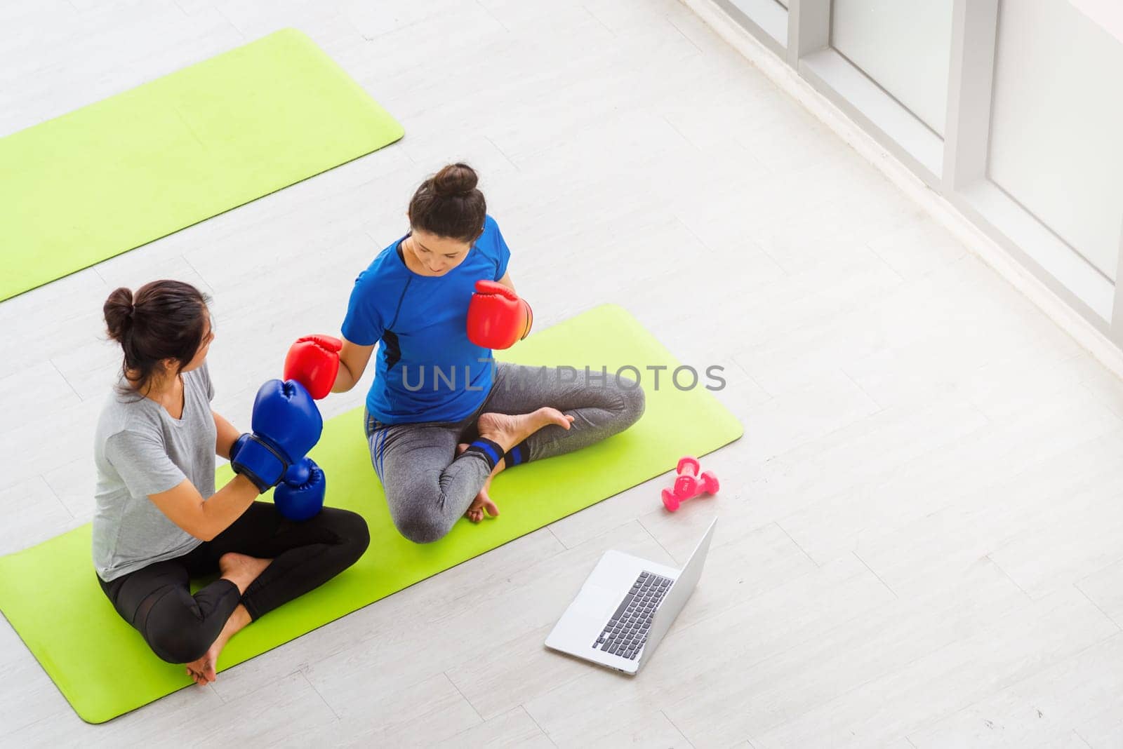 Overhead Asian lifestyle adult and young woman sports fitness boxer wearing gloves on boxing in sportswear look laptop computer for training online indoor yoga studio, sport healthy workout concept