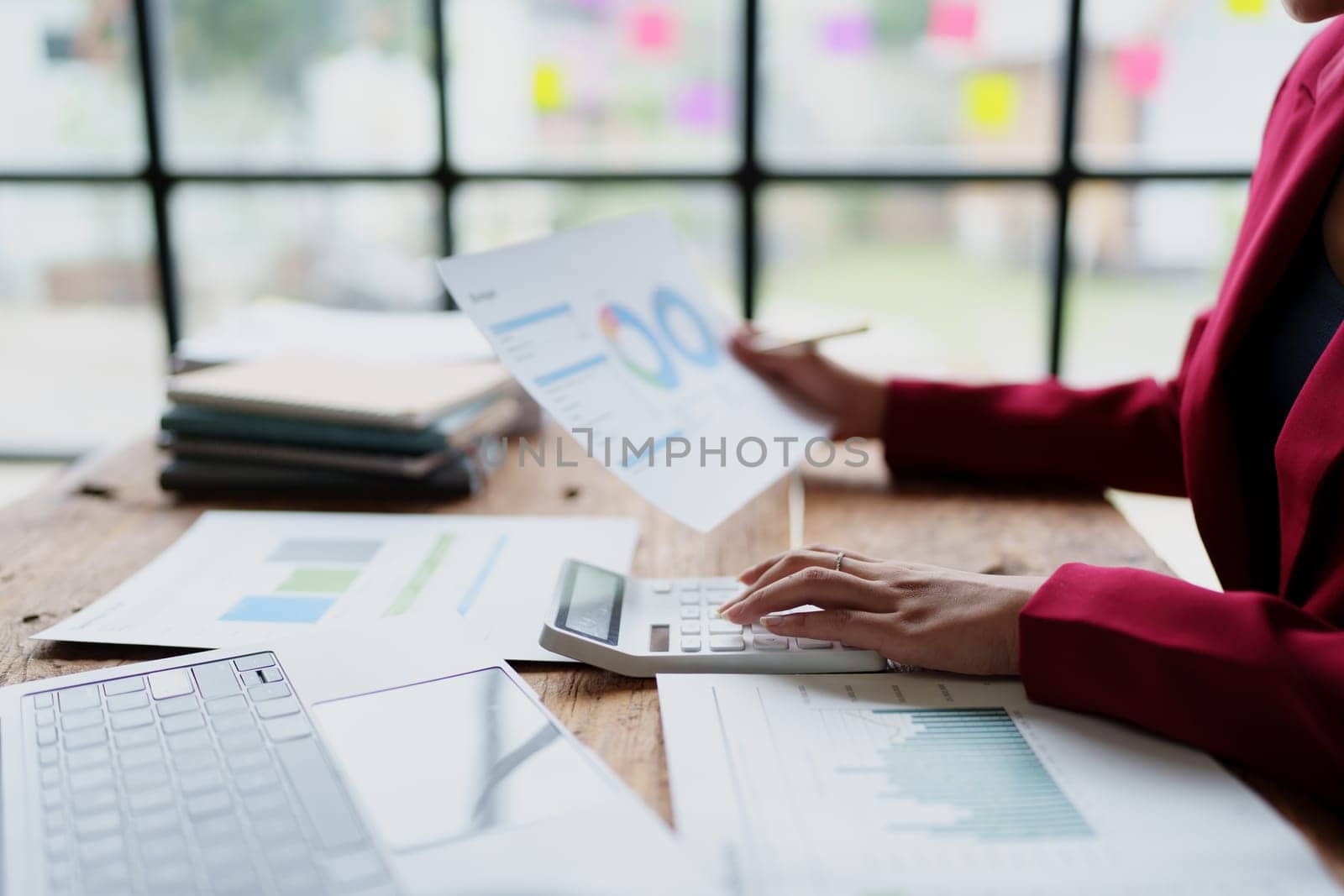 businesswoman or accountant working on calculator and laptop computer to calculate business data during using accountancy document at office by Manastrong
