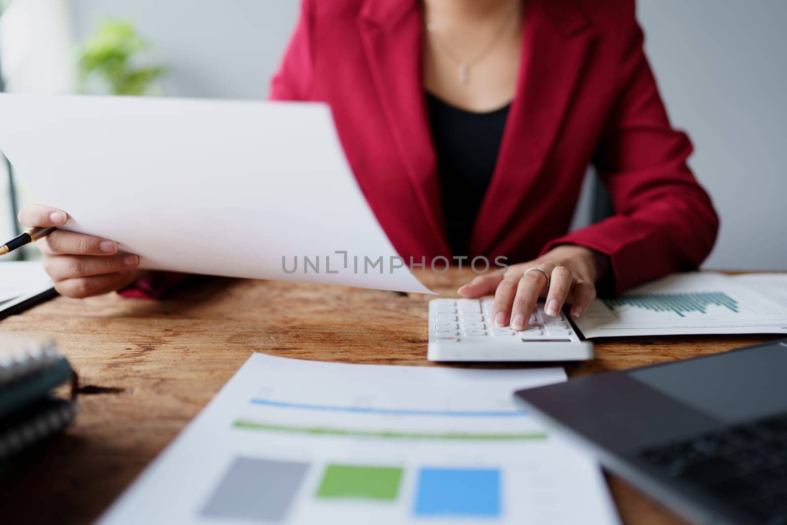 businesswoman or accountant working on calculator and laptop computer to calculate business data during using accountancy document at office by Manastrong