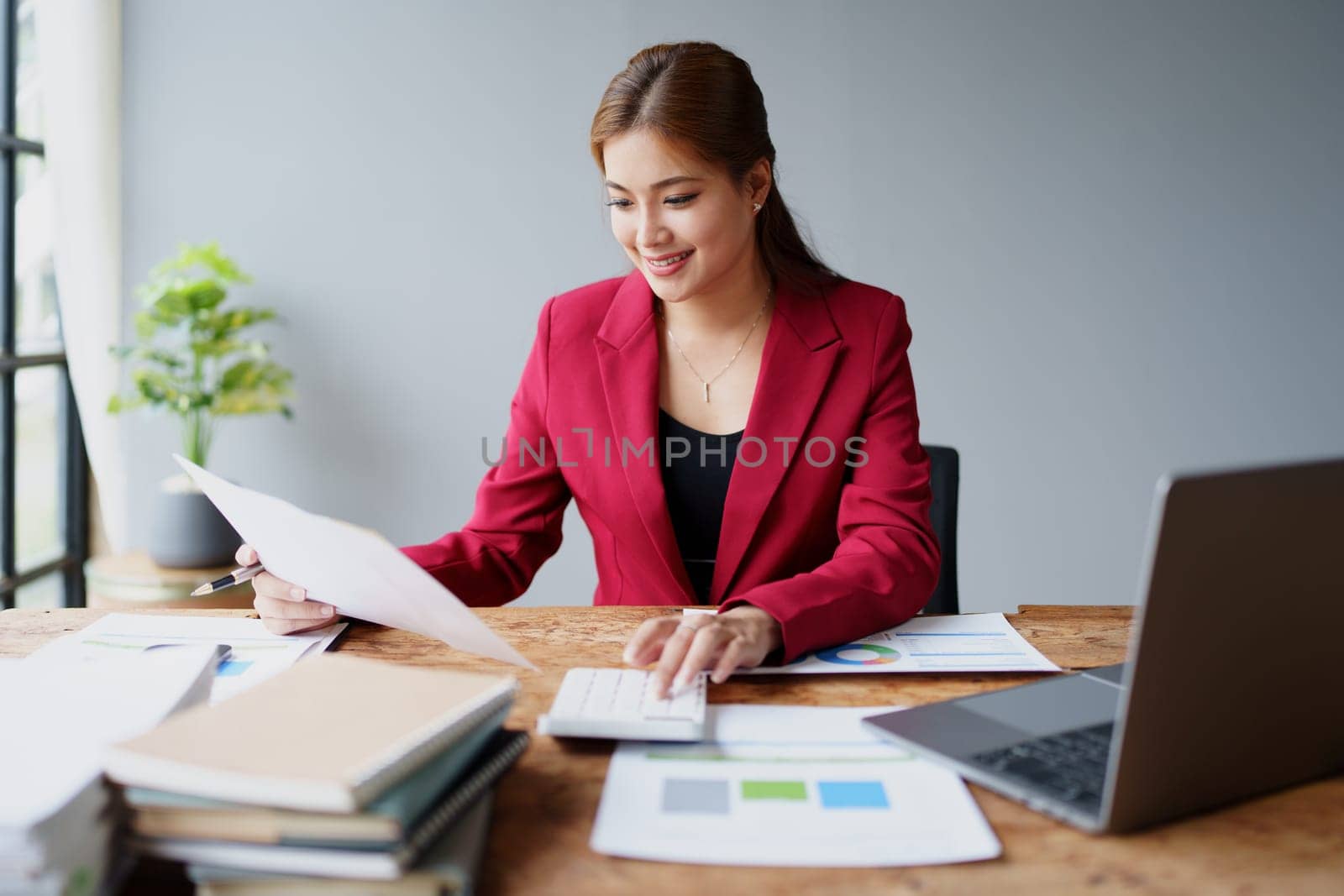 businesswoman or accountant working on calculator and laptop computer to calculate business data during using accountancy document at office by Manastrong