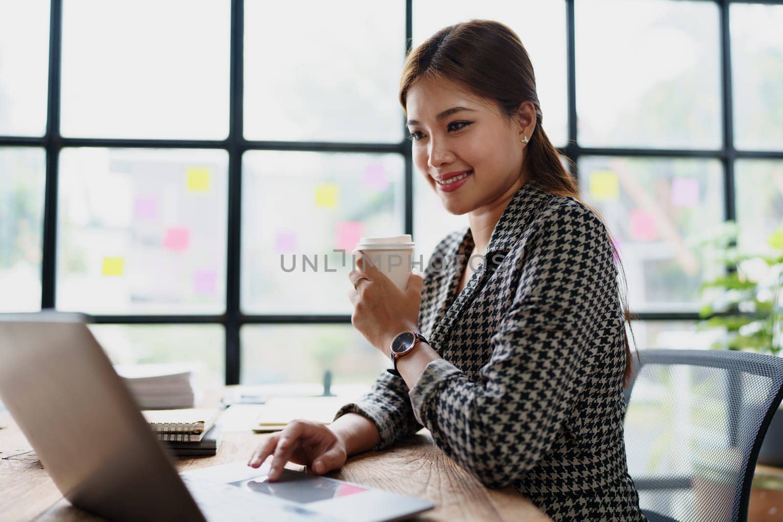 Portrait of a business woman talking on the computer and drinking coffee.