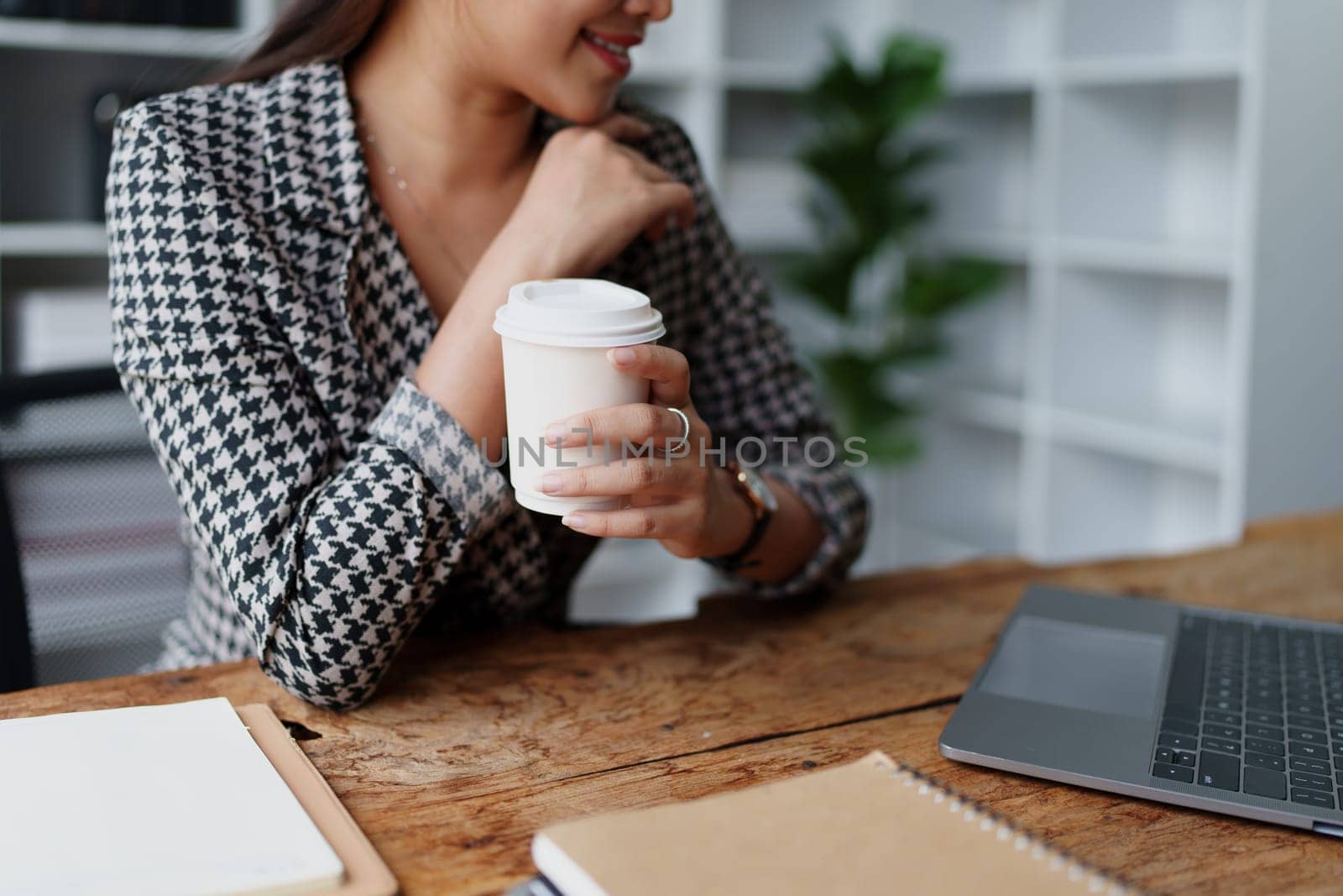 Portrait of a business woman talking on the computer and drinking coffee.