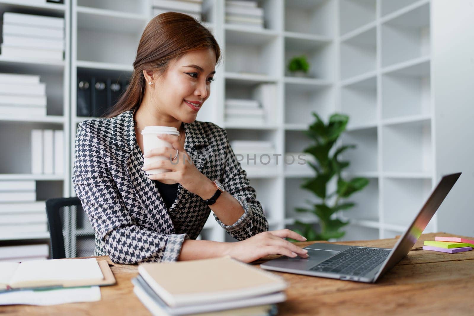Portrait of a business woman talking on the computer and drinking coffee.