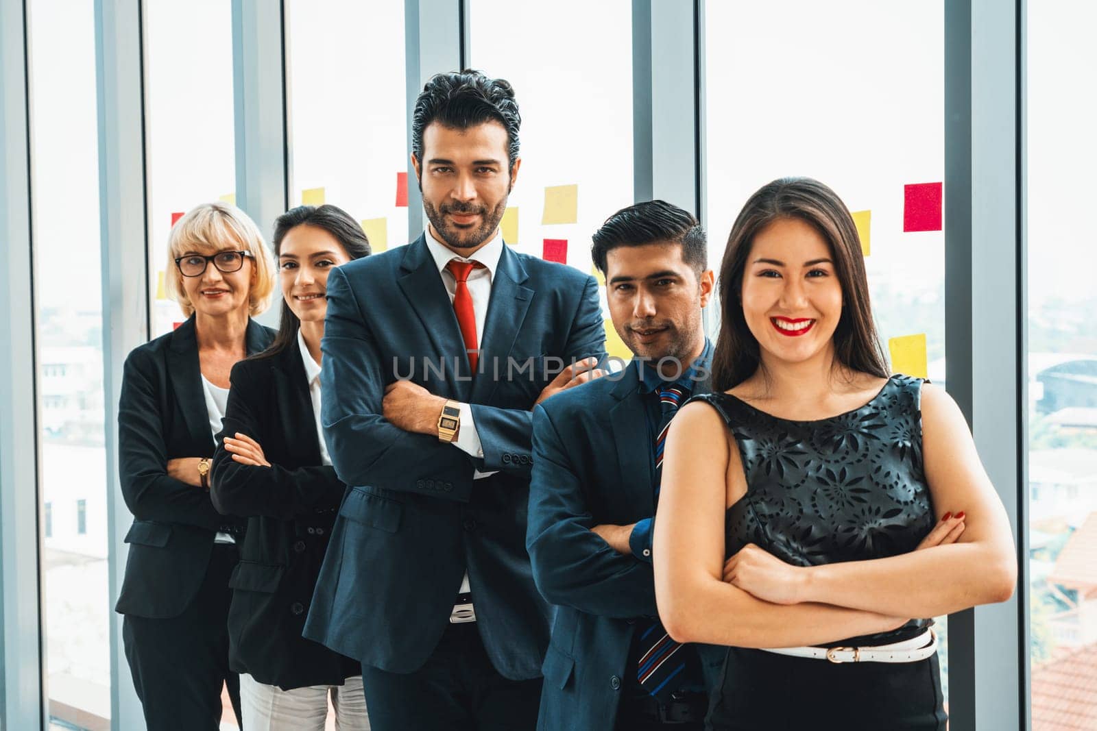 Successful business people standing together showing strong relationship of worker community. A team of businessman and businesswoman expressing a strong group teamwork at the modern office. Jivy
