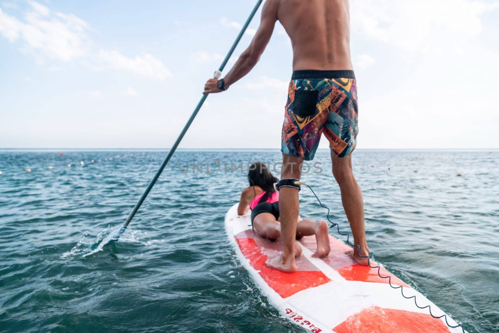 Sea woman and man on sup. Silhouette of happy young woman and man, surfing on SUP board, confident paddling through water surface. Idyllic sunset. Active lifestyle at sea or river