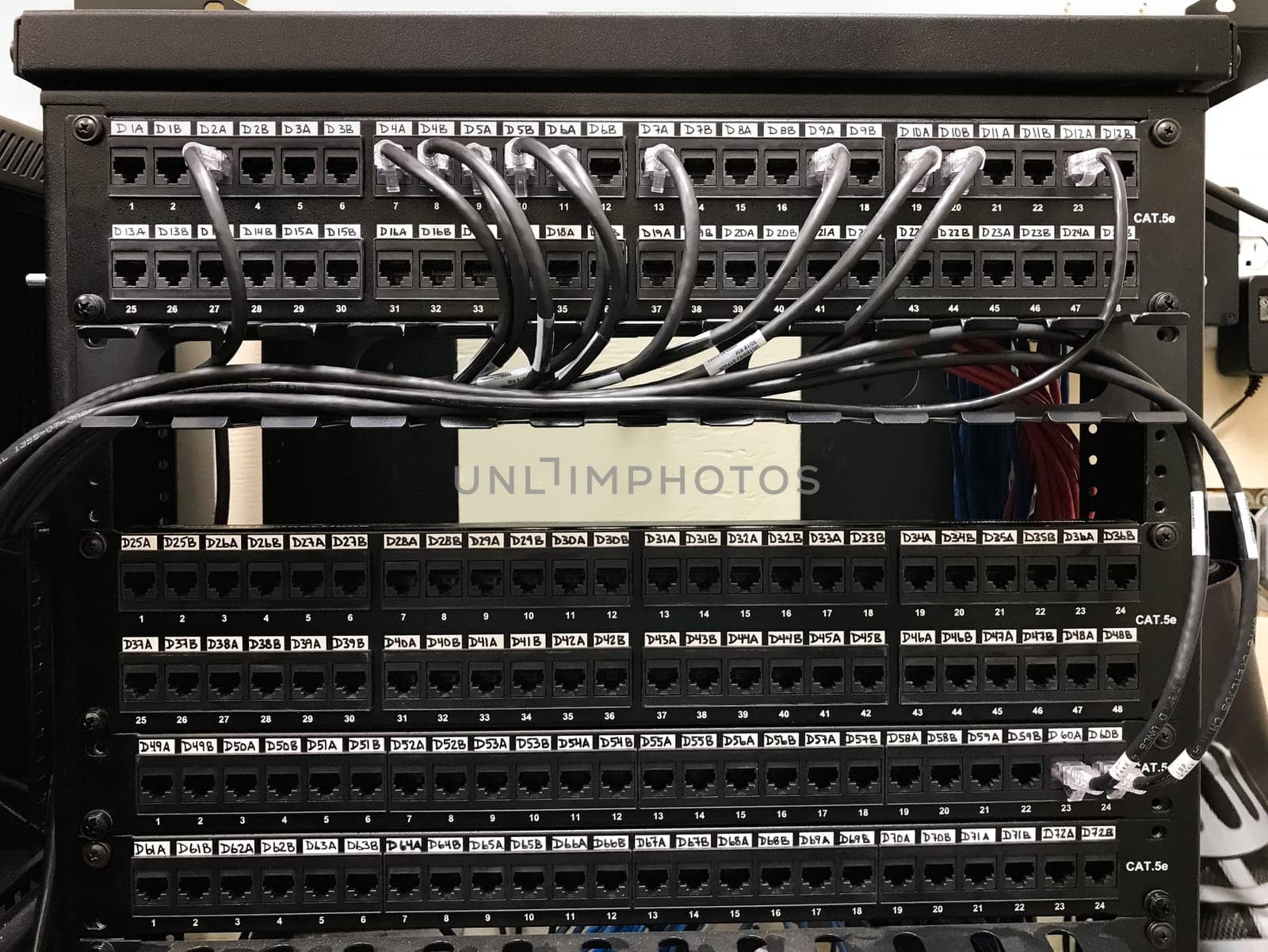 Enumerated ethernet patch panels with cables connected to the ports. Communication closet with patch panels mounted on the rack