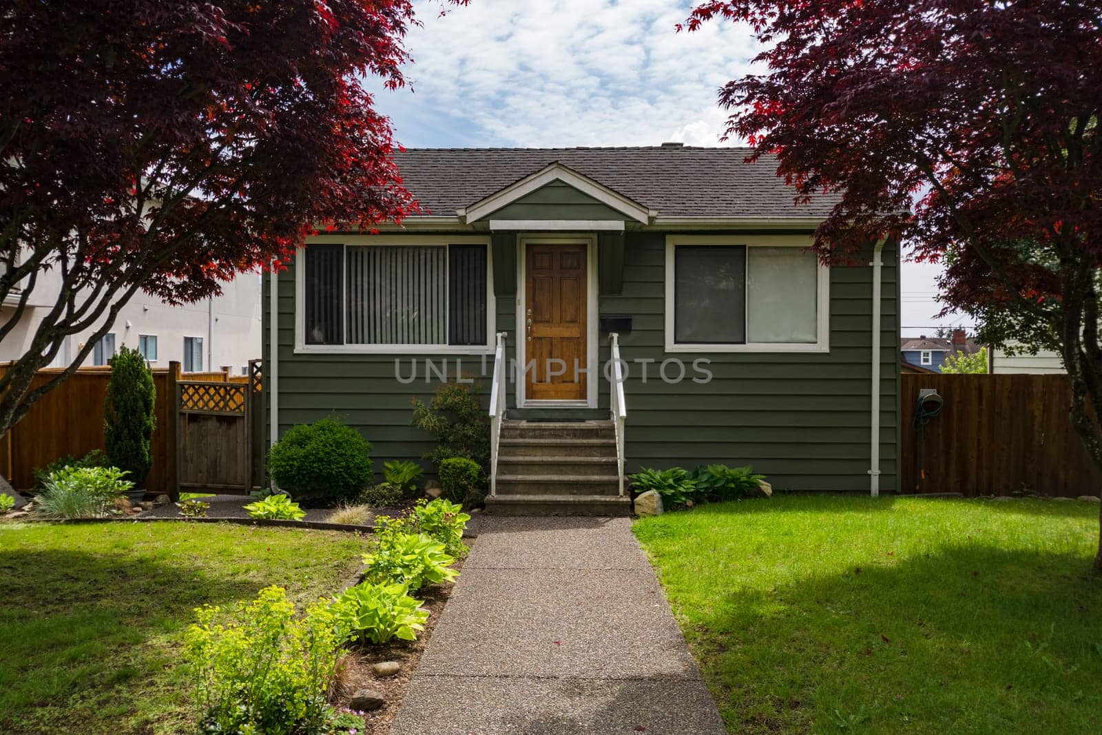 Average residential house with concrete pathway over the front yard and wooden entrance door