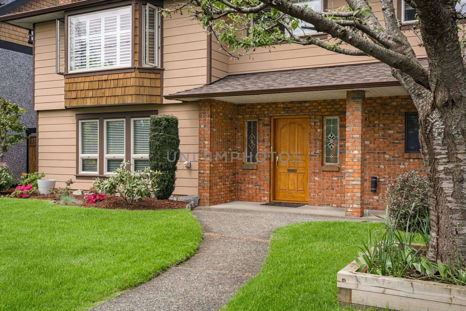 Nice main entrance of old family house with brick textured wall and concrete pathway over front yard lawn