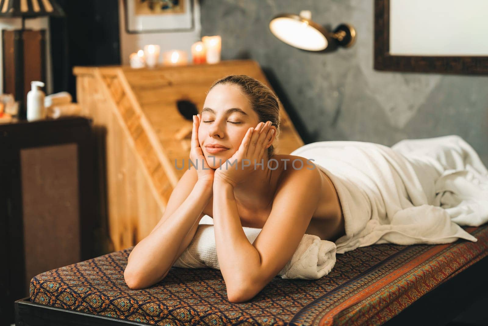 Beautiful woman lies on spa bed in front of wooden sauna cabinet. Tranquility. by biancoblue
