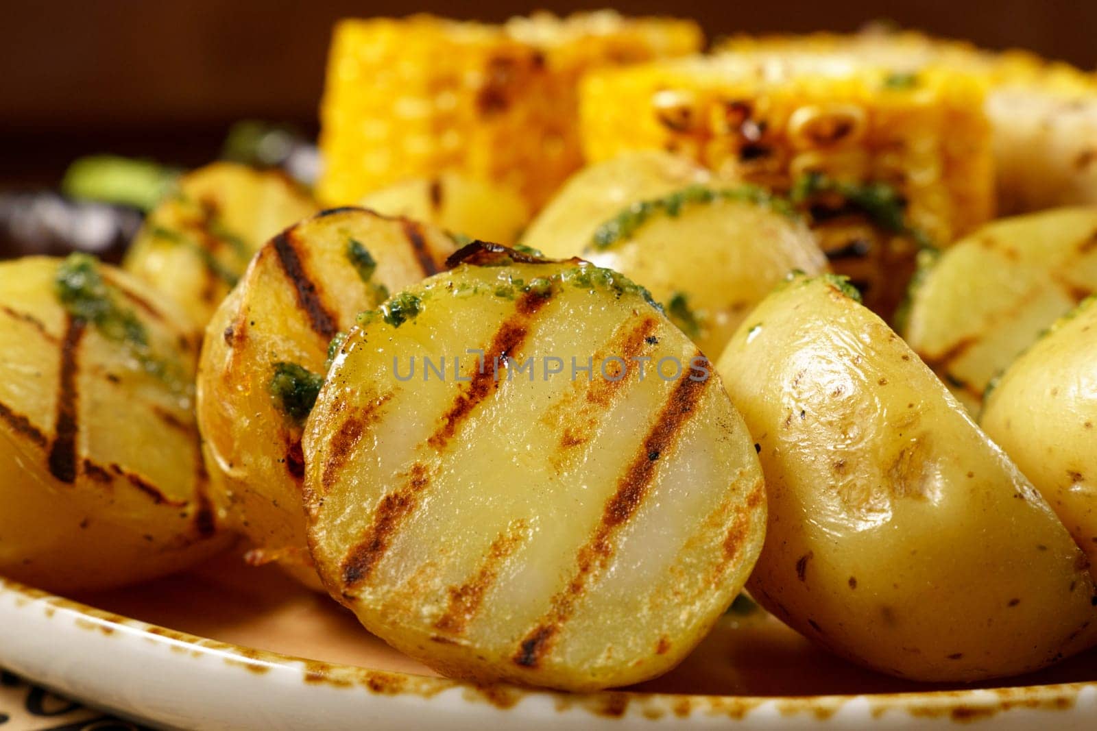 Grilled baked potatoes with corn, on a large frying pan. Food court