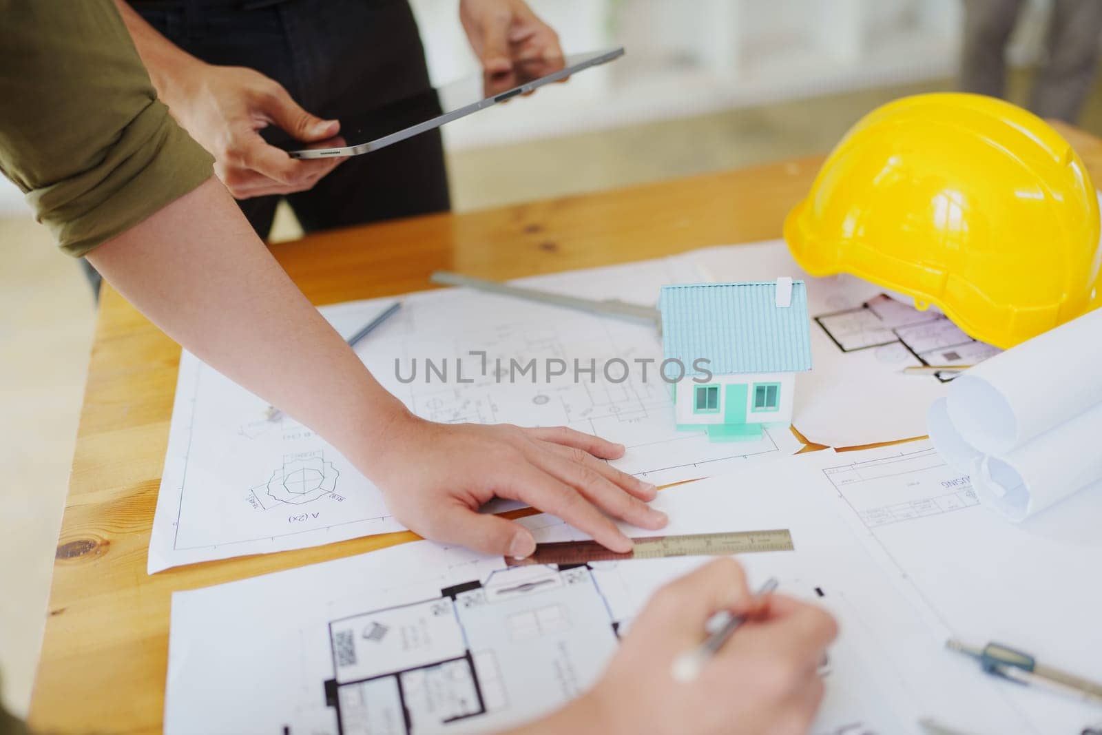 multi ethnic engineer brainstorming and measuring for cost estimating on blueprint and floor plan drawings about design architectural and engineering for houses and buildings by Manastrong