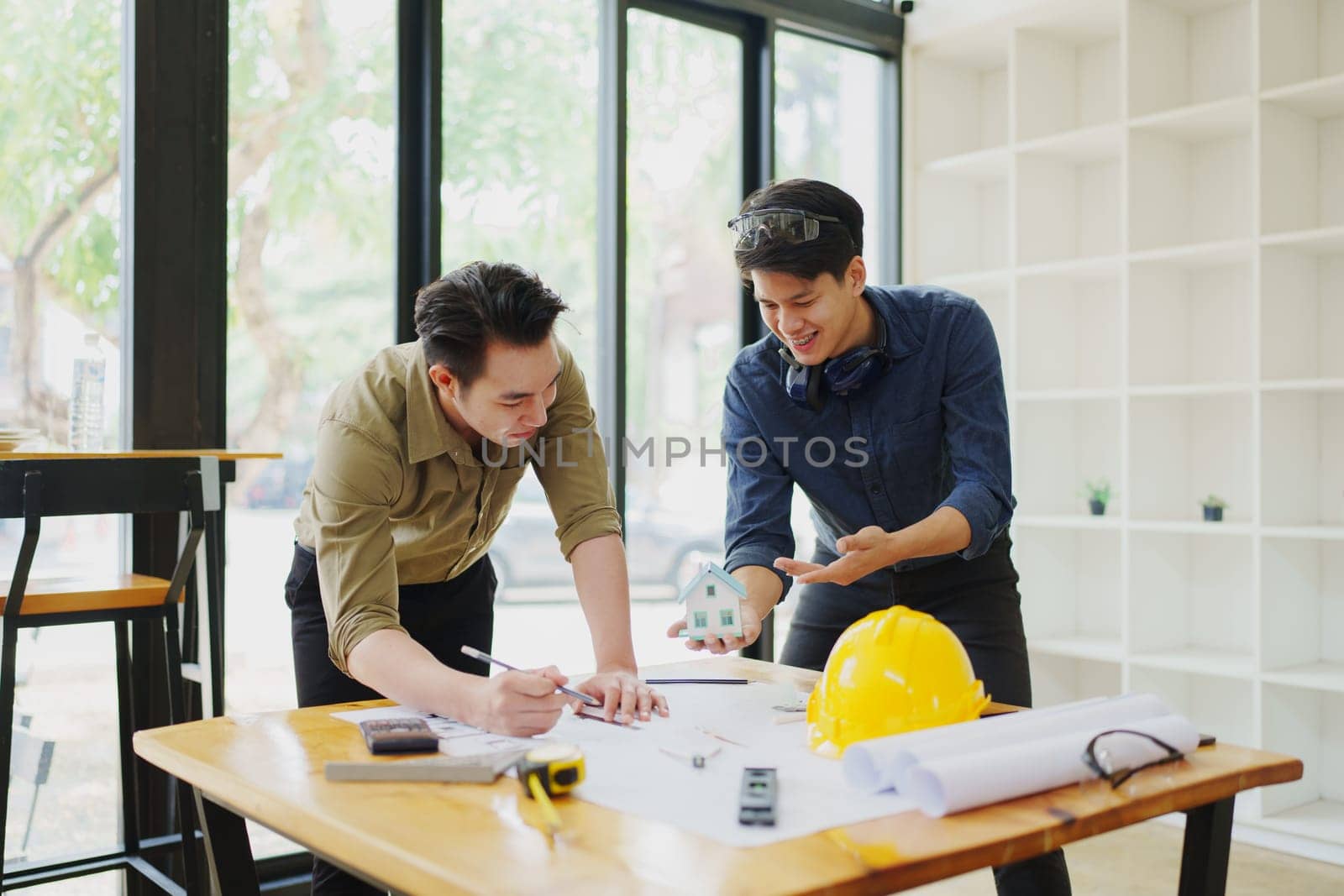 multi ethnic engineer brainstorming and measuring for cost estimating on blueprint and floor plan drawings about design architectural and engineering for houses and buildings.