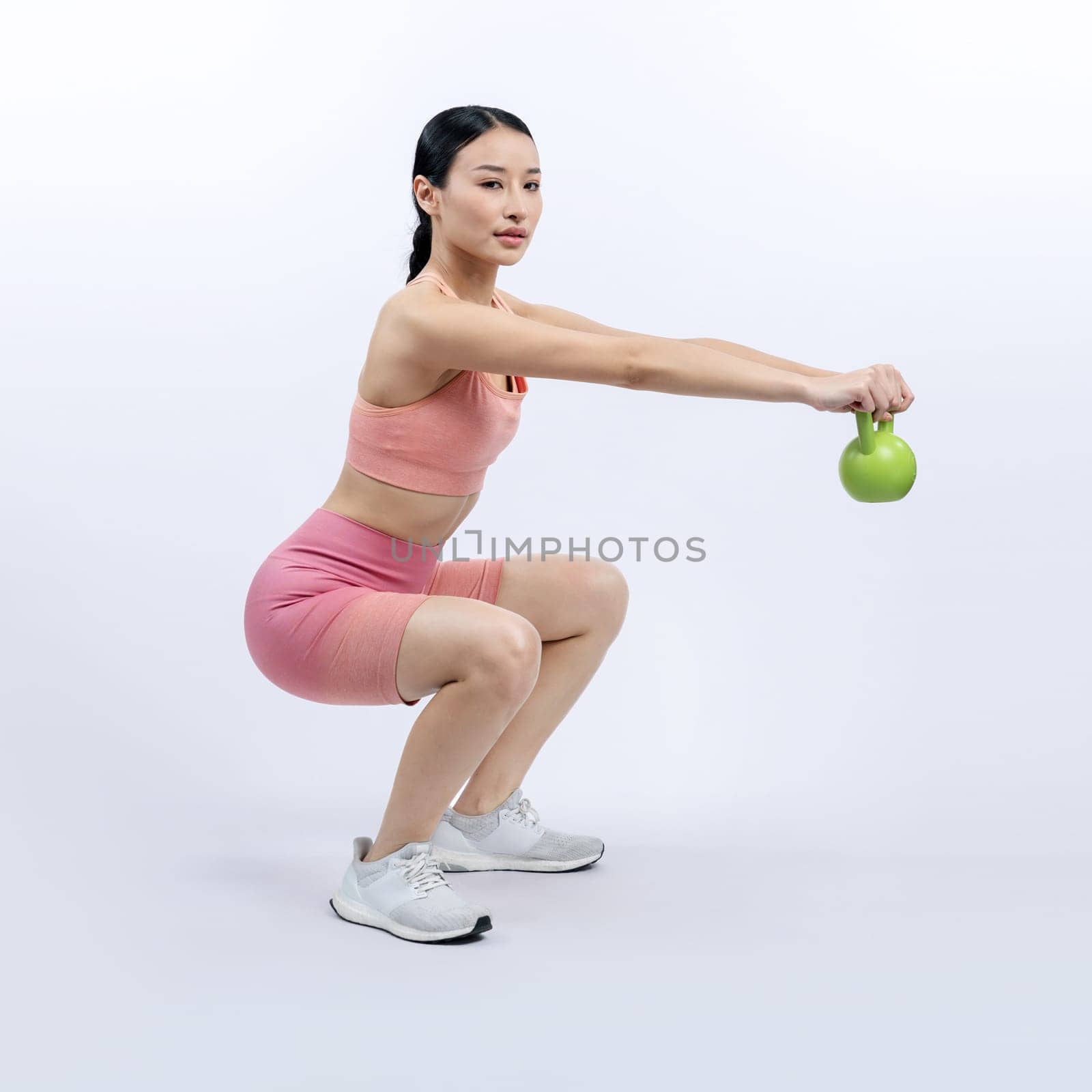 Vigorous energetic woman doing yoga with kettlebell weight exercise. by biancoblue