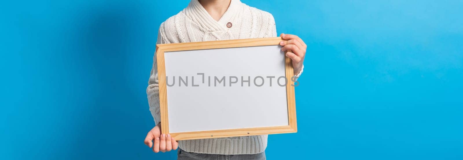 Banner boy with blank canvas. Copy space on canvas board for image or message. Kid holds mockup poster and standing over blue background. by Satura86