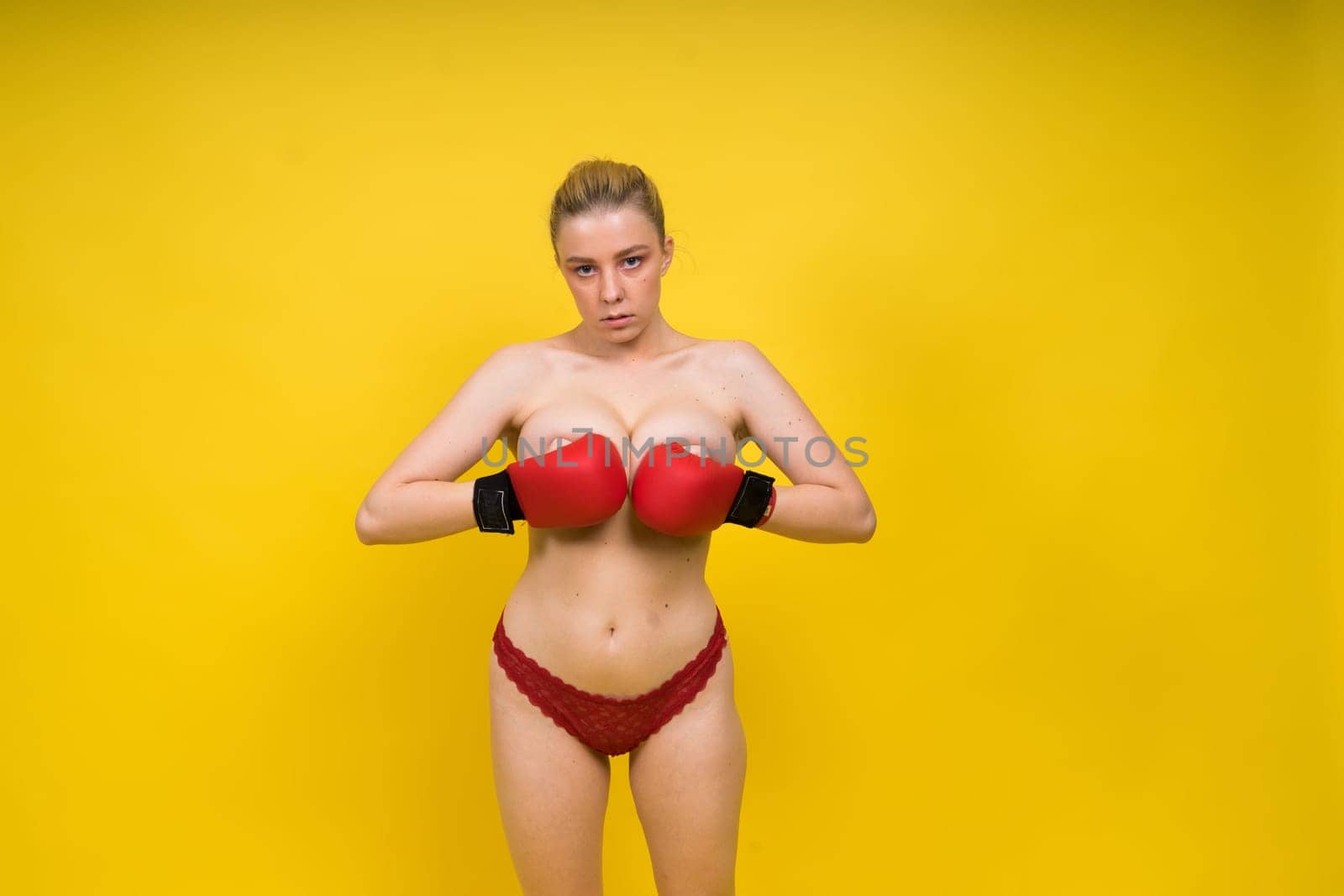 Seductive young and fit female fighter posing in gloves in a studio