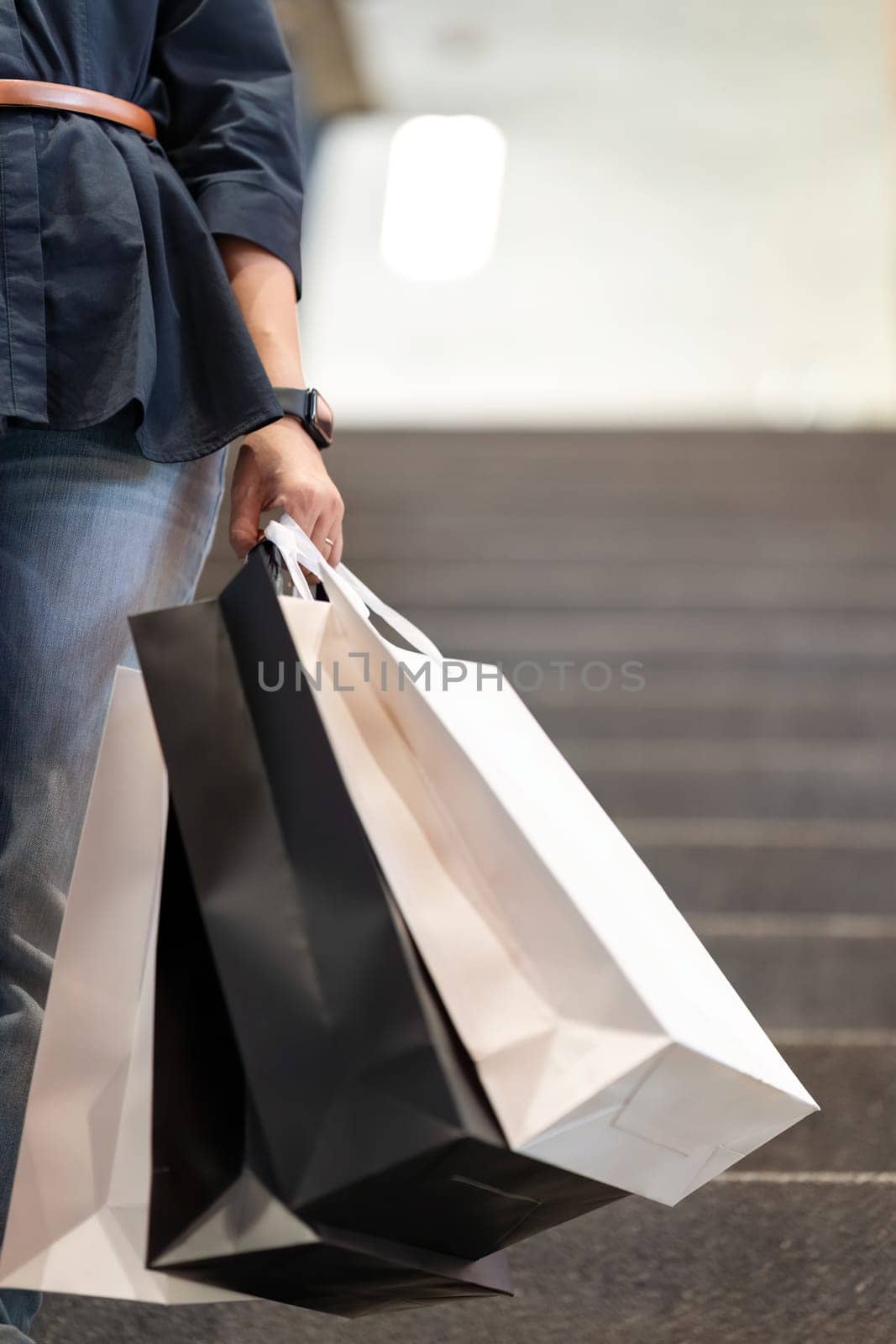 Close up of woman hand holding shopping bag while walking near mall on holidays Black Friday by nateemee