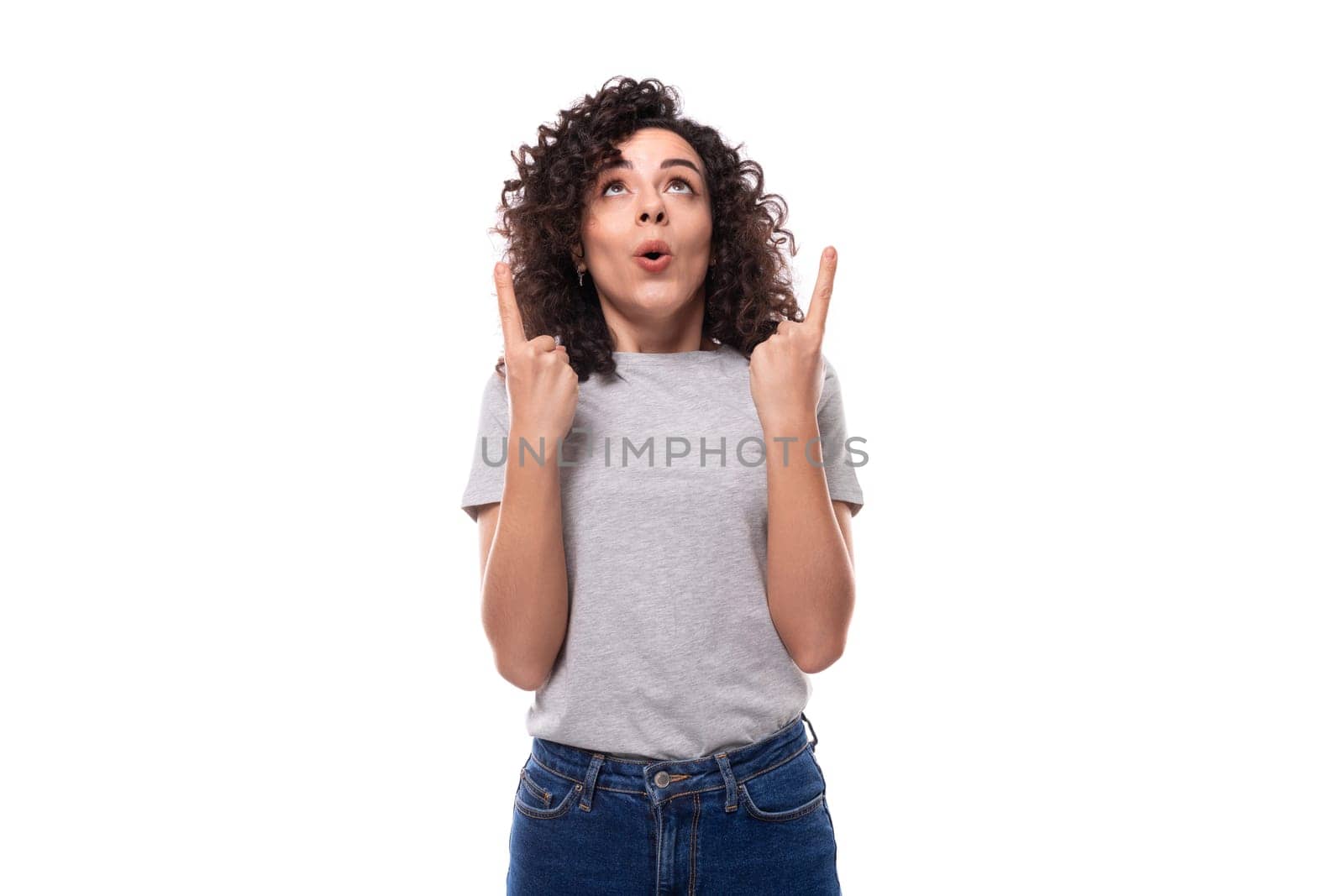 young smiling pretty brunette curly lady in a gray basic t-shirt on a white background with copy space.