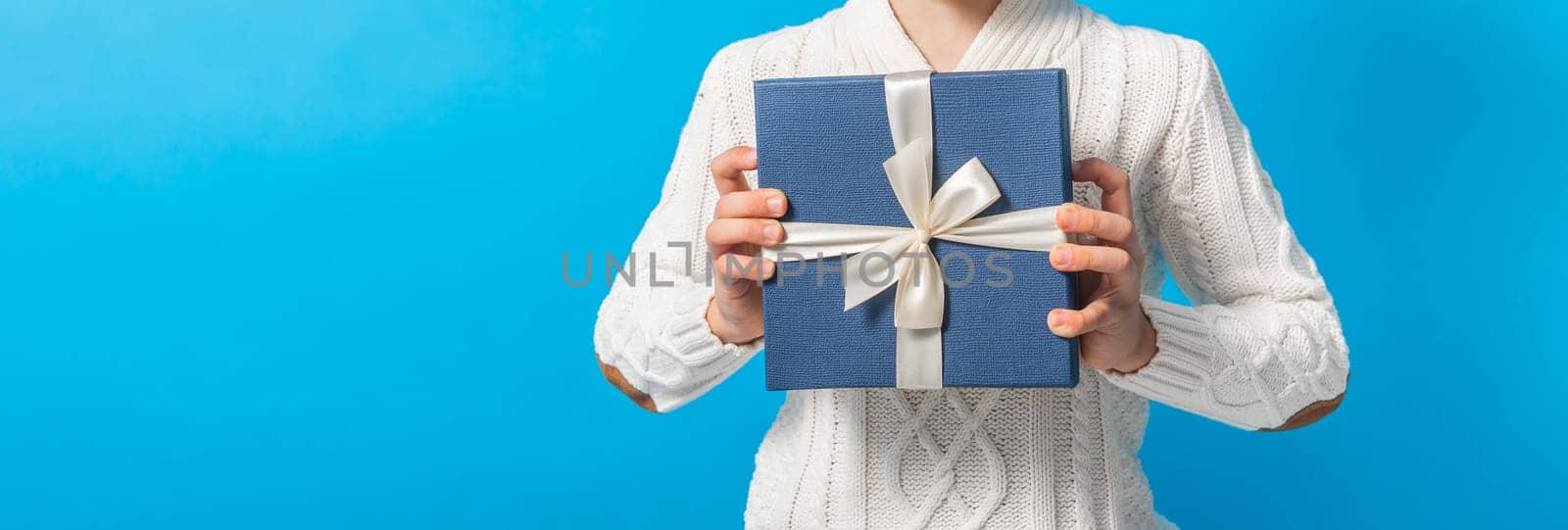 Child boy gift. Kid close-up holds gift box. Shopping time. Banner header with copy space on blue background. by Satura86