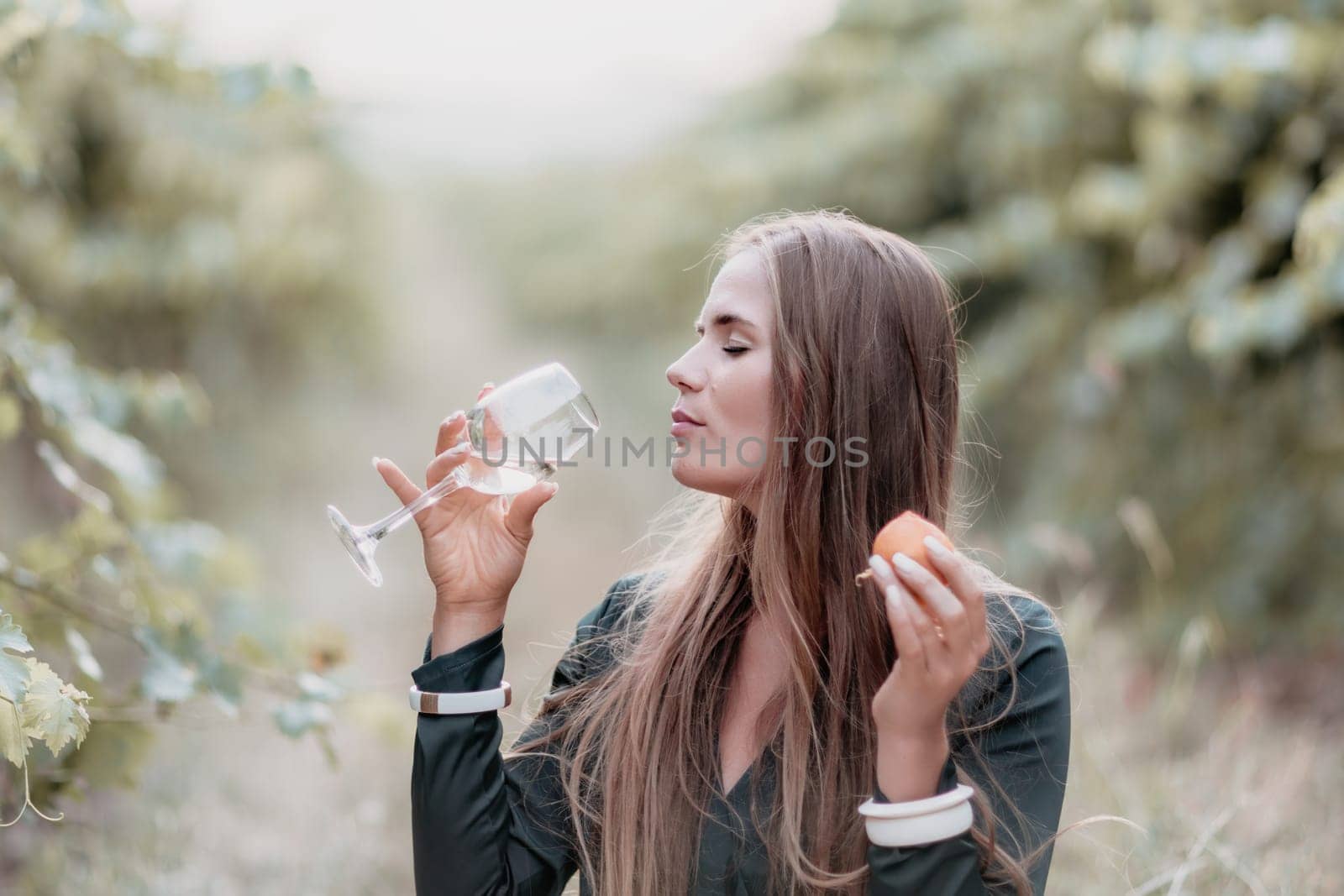 Woman picnic vineyard. Happy woman with a glass of wine at a picnic in the vineyard, wine tasting at sunset and open nature in the summer. Romantic dinner, fruit and wine. by panophotograph