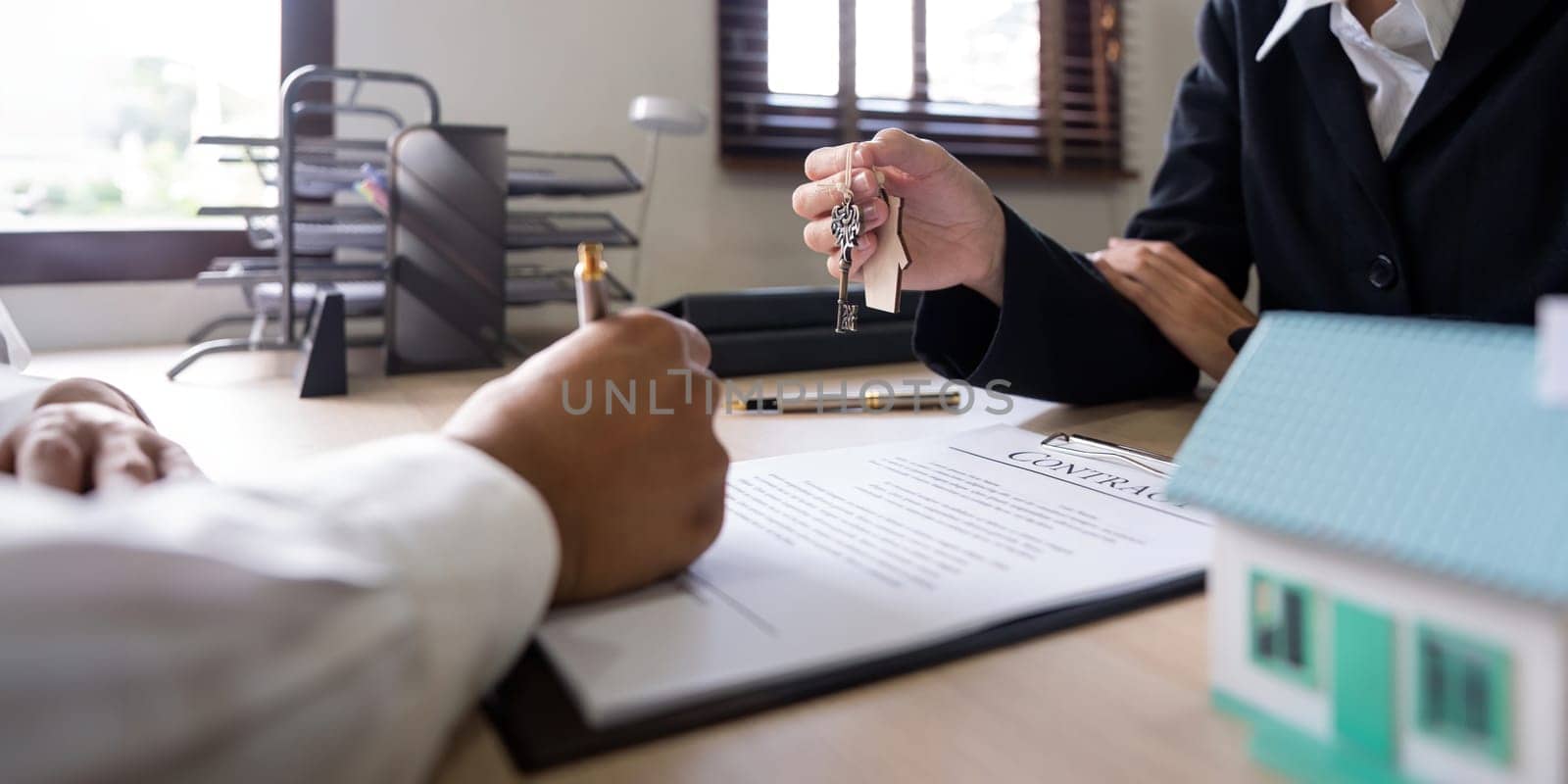 Real estate agents agree to purchase a home and give keys to clients at office. Concept agreement.