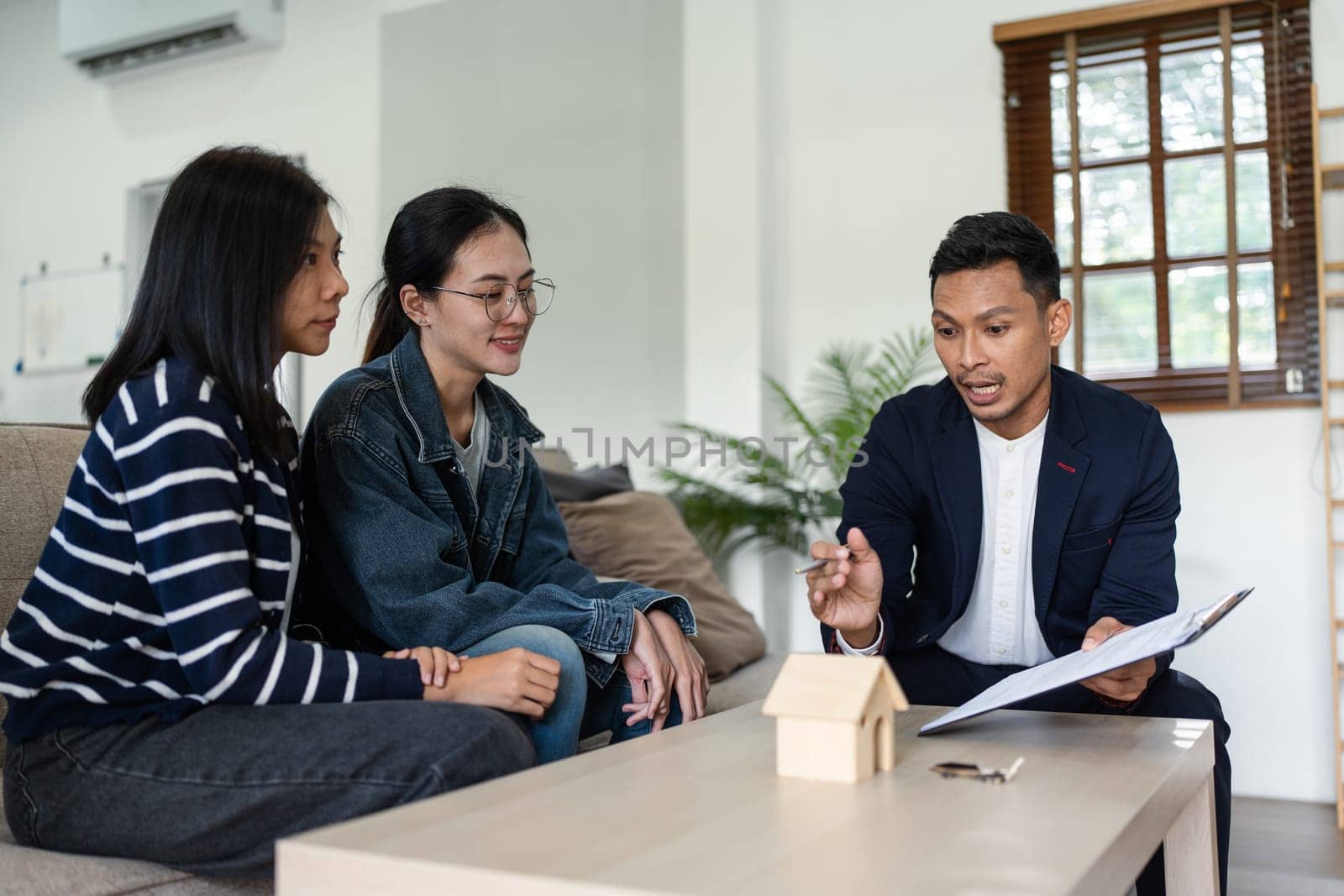 young lesbian married couple discussing agreement with skilled real estate agent or broker. Professional financial advisor or saleswoman explaining contract detail.