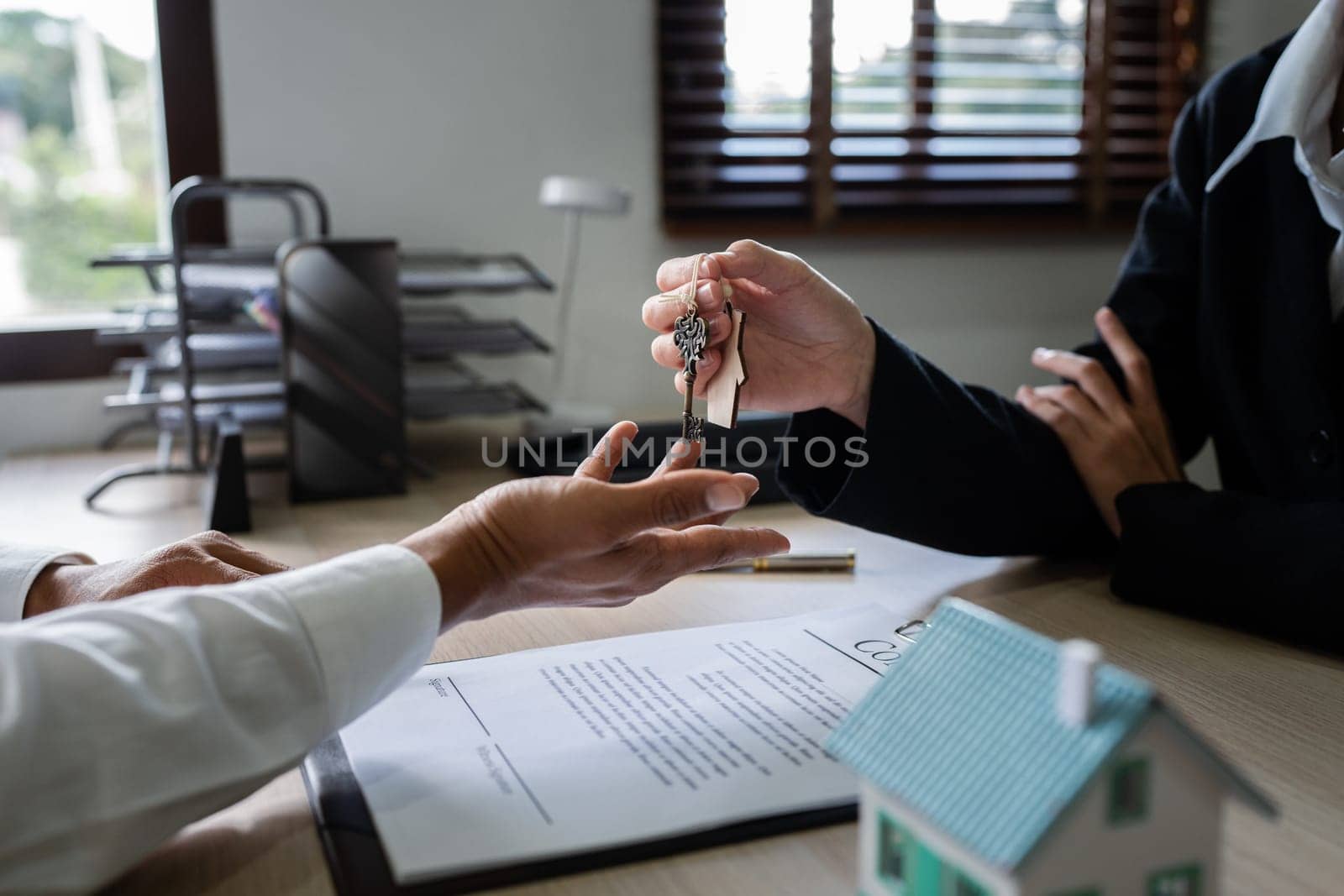 Happy real state agent giving new house key to a young couple. Real estate concept.