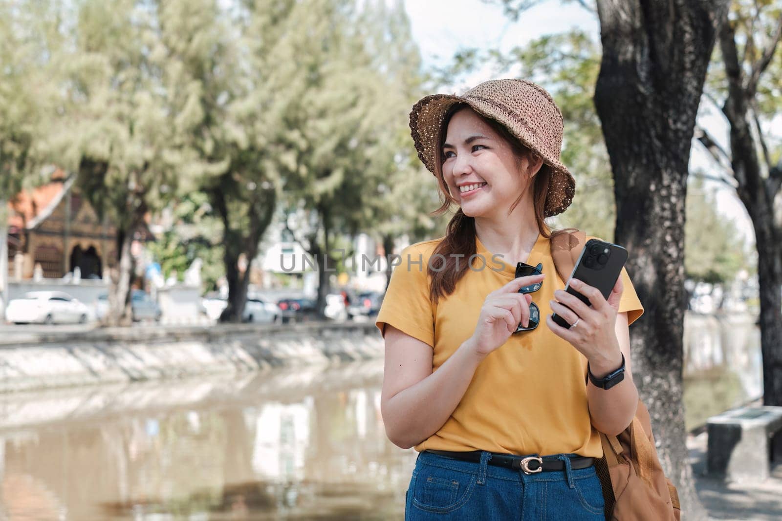Young Asian tourist walking along city streets and holds a mobile phone on the payment by wichayada