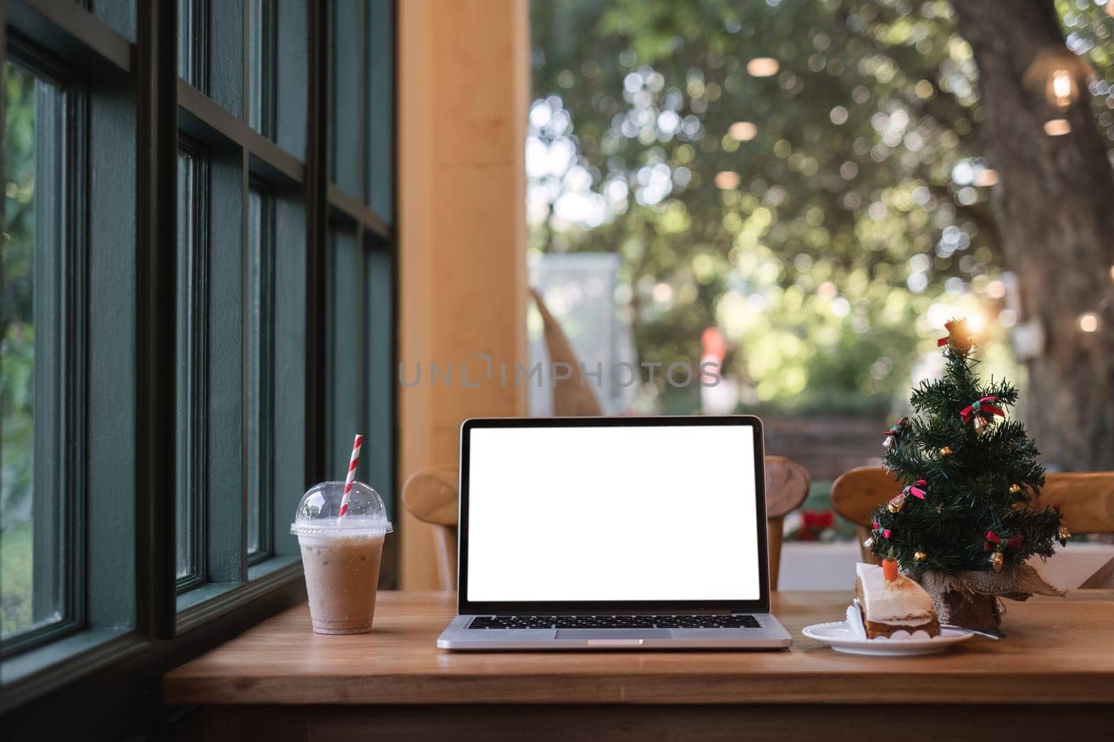 Laptop with blank white screen on table Workspace in modern office concept and Christmas festival by wichayada