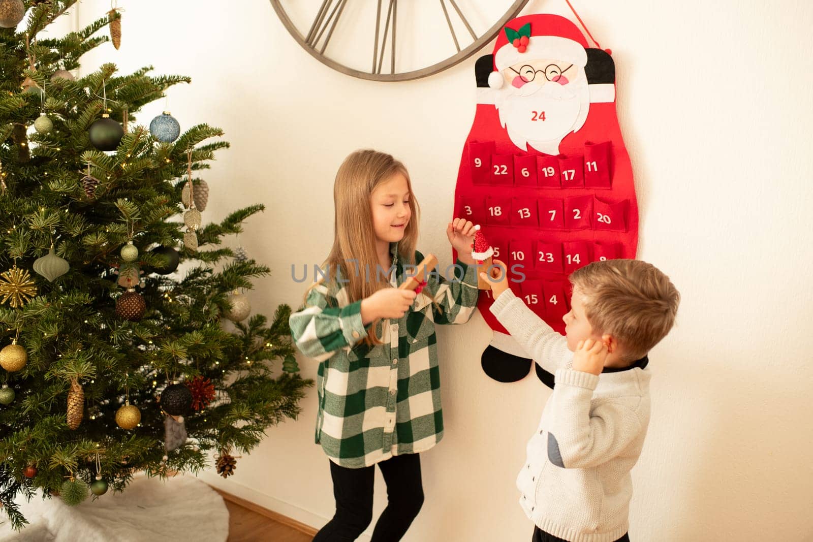 Children found gifts in Felt santa claus advent calendar near christmas tree by Godi