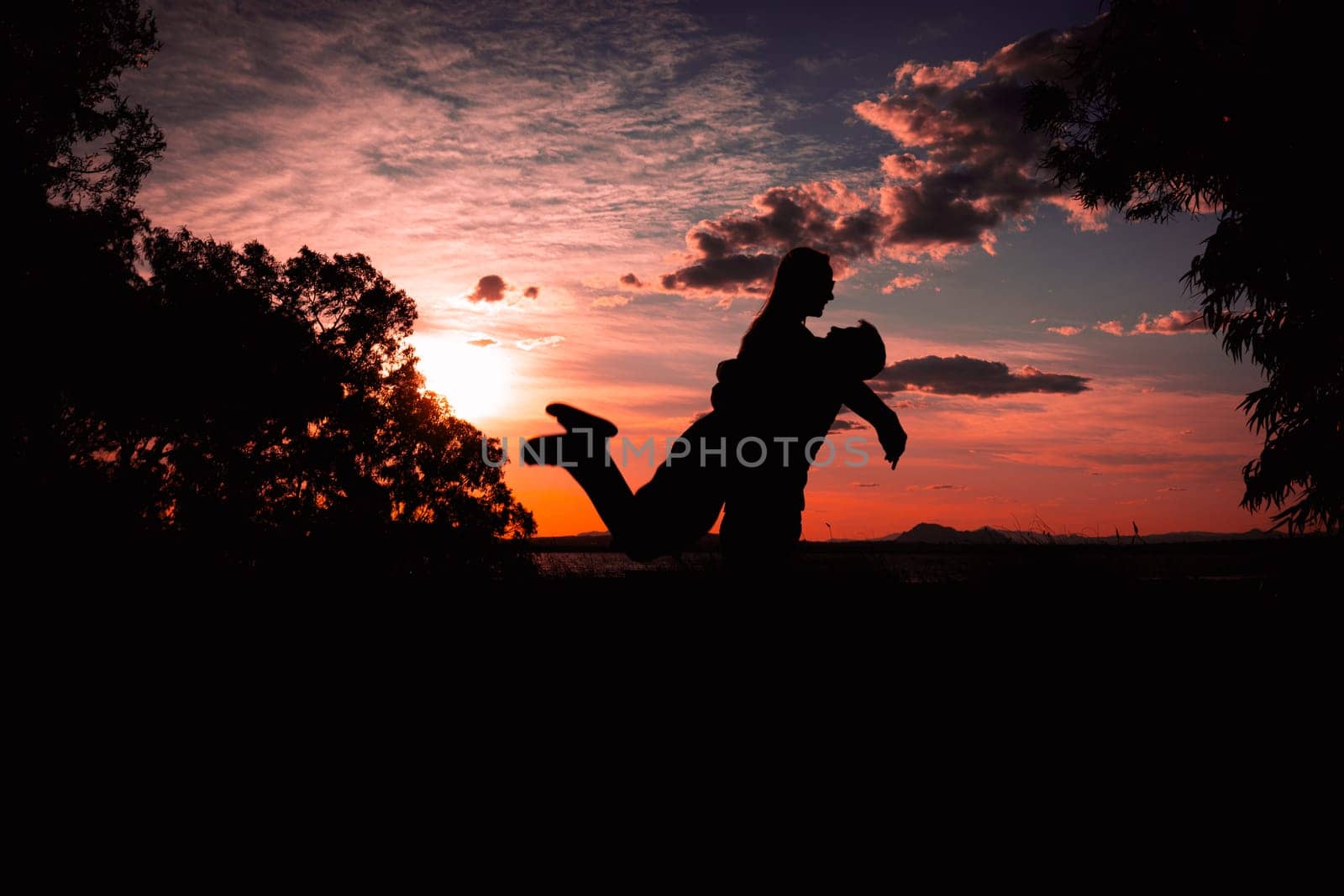 silhouette of a couple in love at sunset against the backdrop of nature, there is a place for the inscription, the guy is holding the girl in his arms, a happy couple silhouette. High quality photo