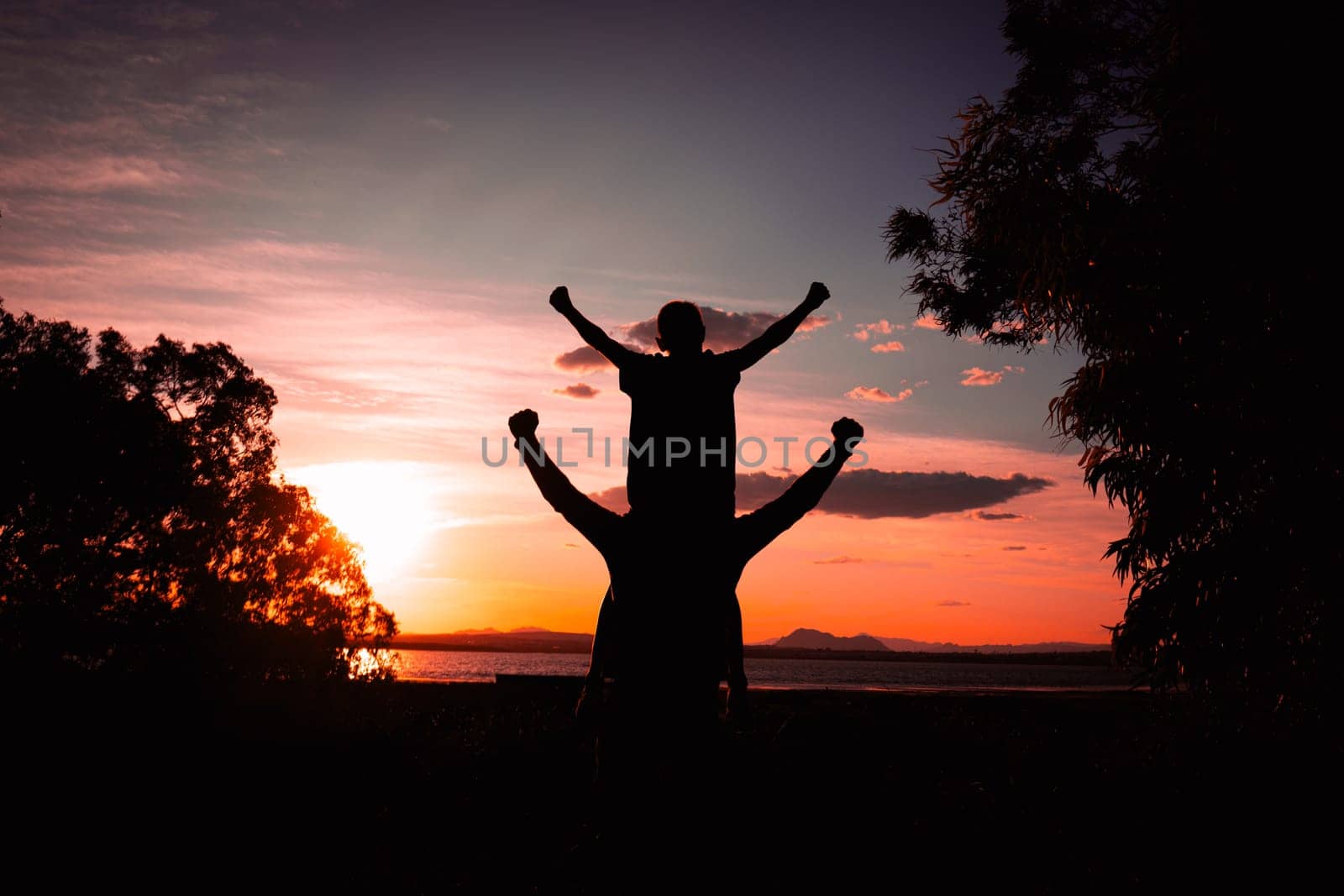 Father and son walking on the field at the sunset time. Concept of friendly family. High quality photo