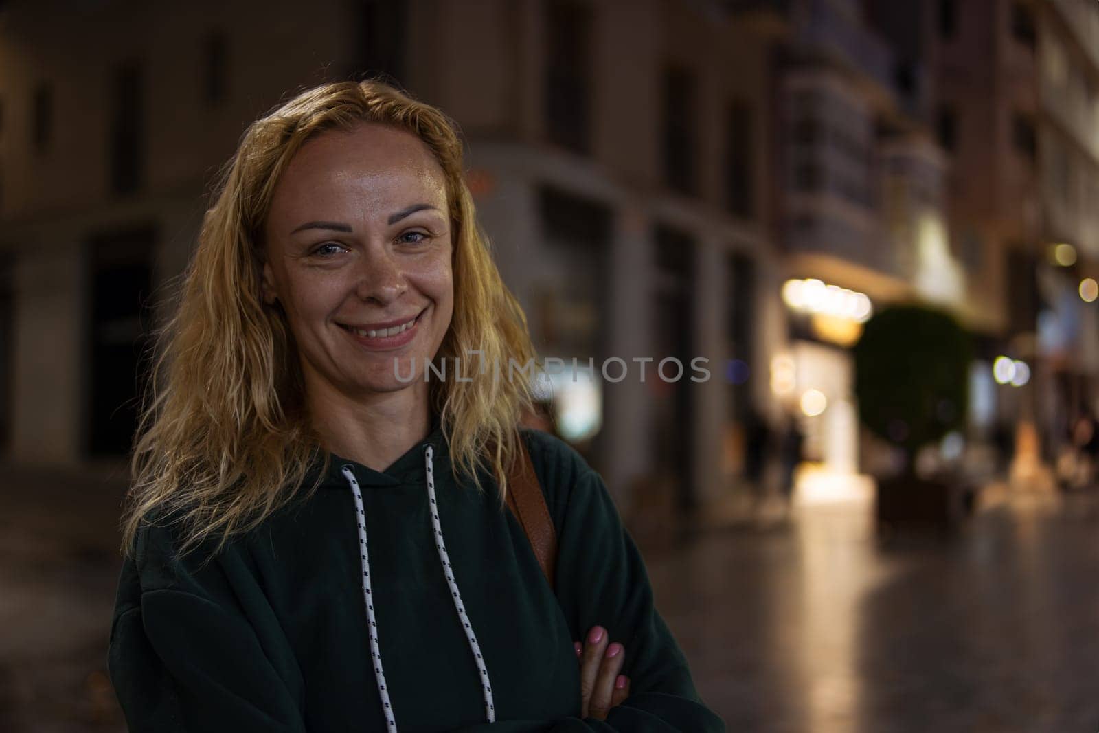 portrait of a girl with blond hair in a green jacket, the girl stands on the street in the evening by PopOff