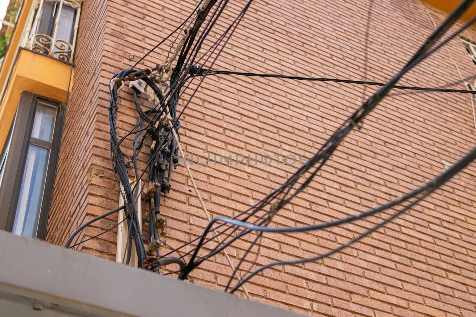 many electrical wires on the wall of a multi-story building by PopOff