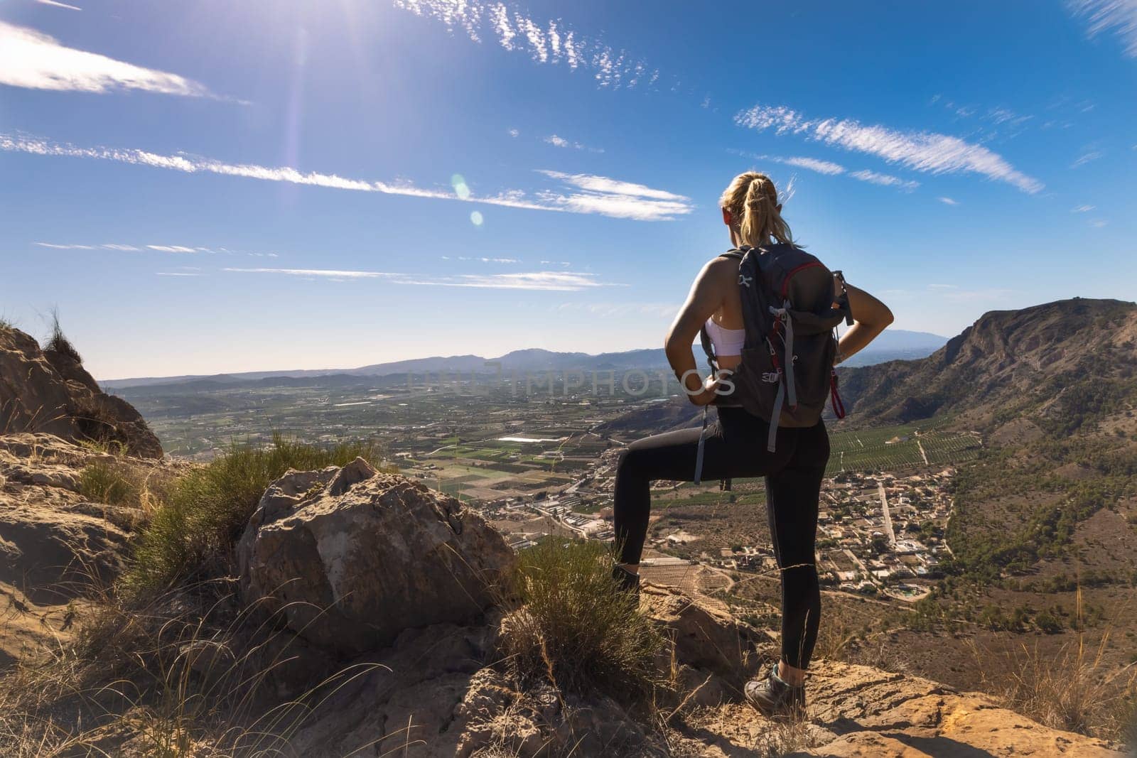 Hiker with backpack standing on top of the mountain and enjoying valley view at sunrise. High quality photo