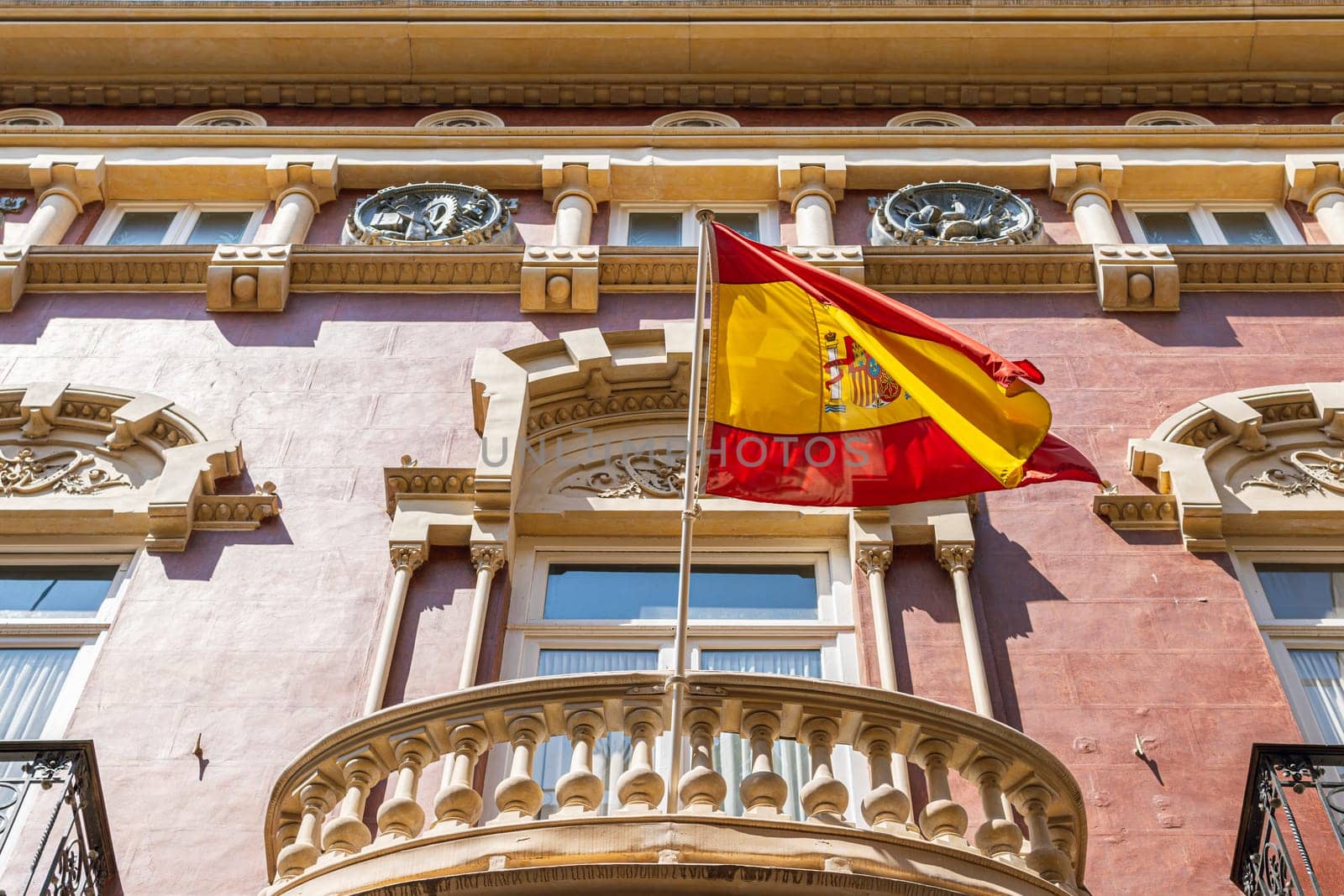 Low angle shot spain flag waving at top of building. by PopOff