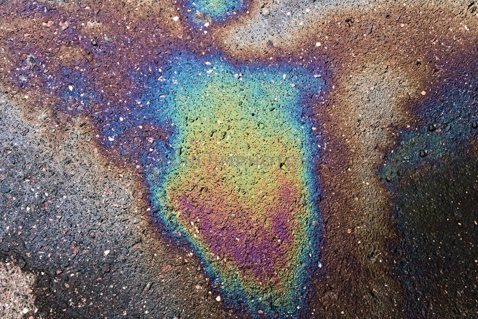 Textured stain of fuel or oil on wet asphalt on a rainy day